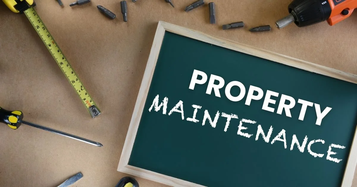 A chalkboard with the words 'Property Maintenance' written on it, surrounded by tools like a measuring tape, screwdriver, drill, and screwdriver bits, on a brown surface.