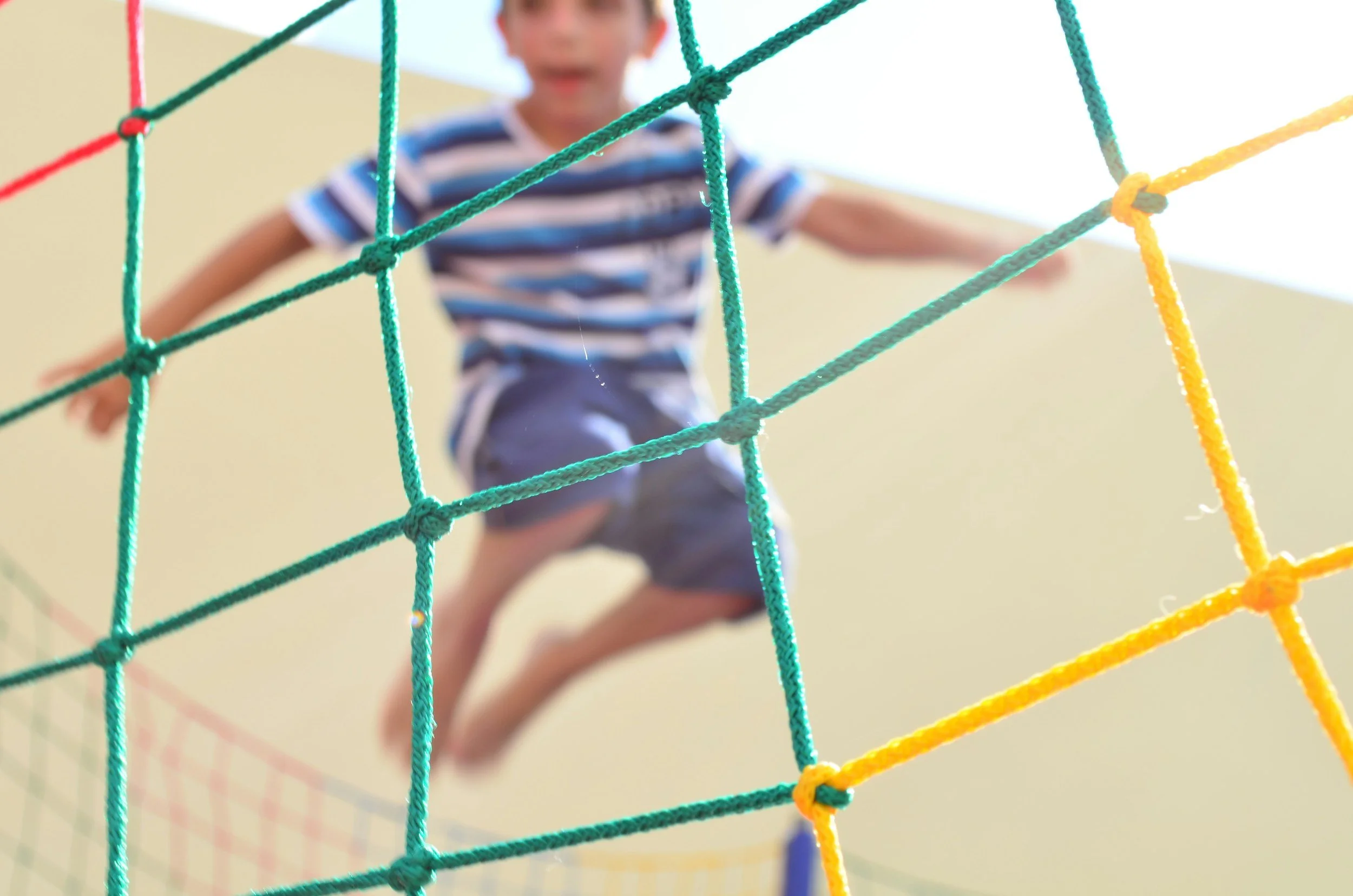 Child climbing on outdoor play equipment during a physical play activity, supporting confidence and regulation in a therapeutic environment in Bourne.