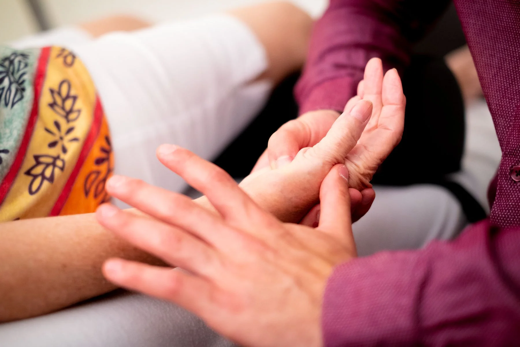 Un ostéopathe tiens la main de sa patiente pendant un traitement.