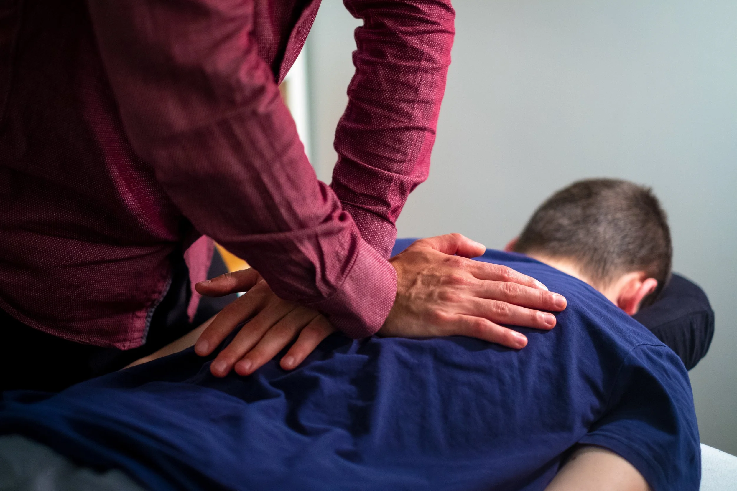 Une personne reçoit une massage sur le dos par un ostéopathe.