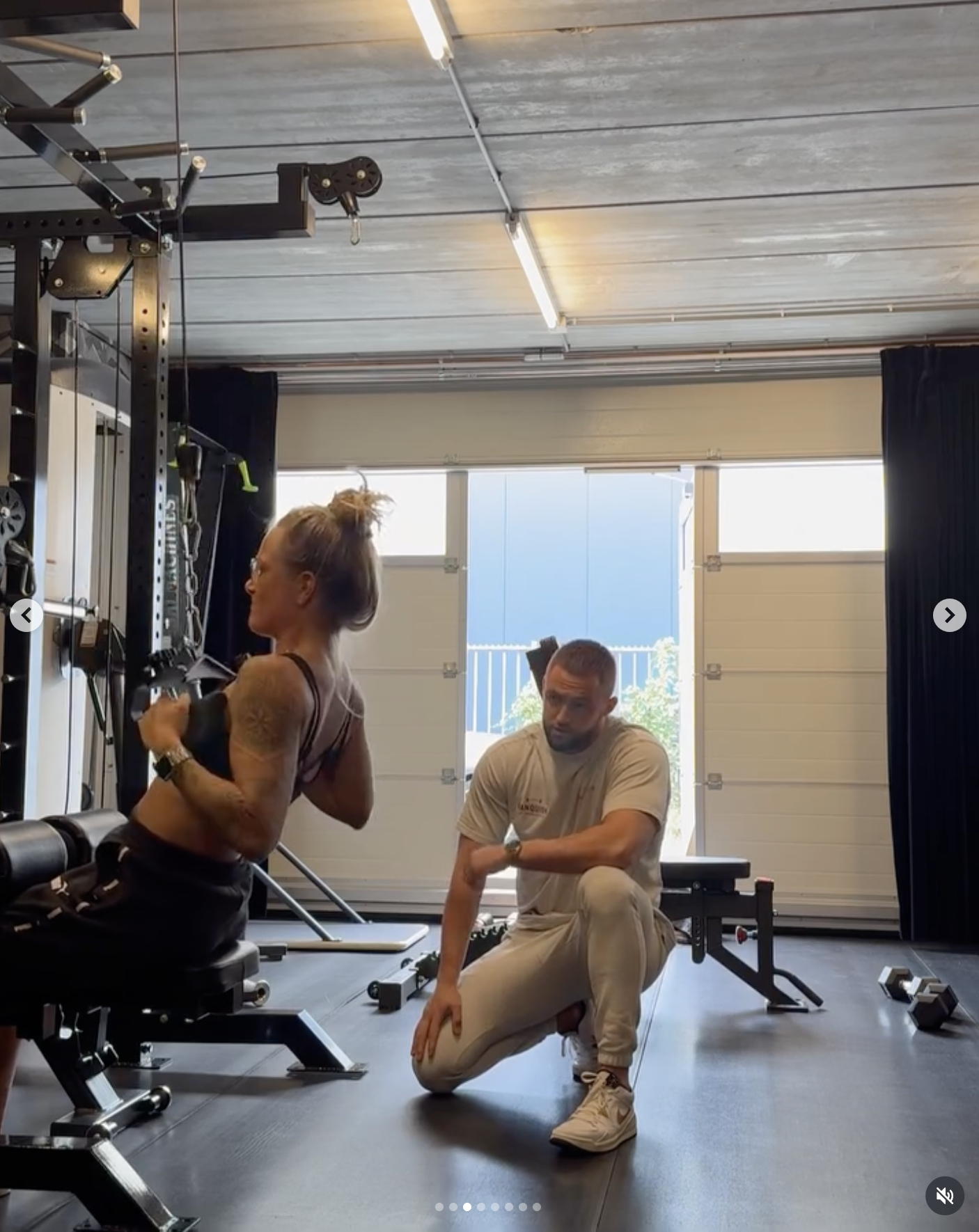 Trainer Mike ondersteunt vrouwelijke klant bij pull down oefening