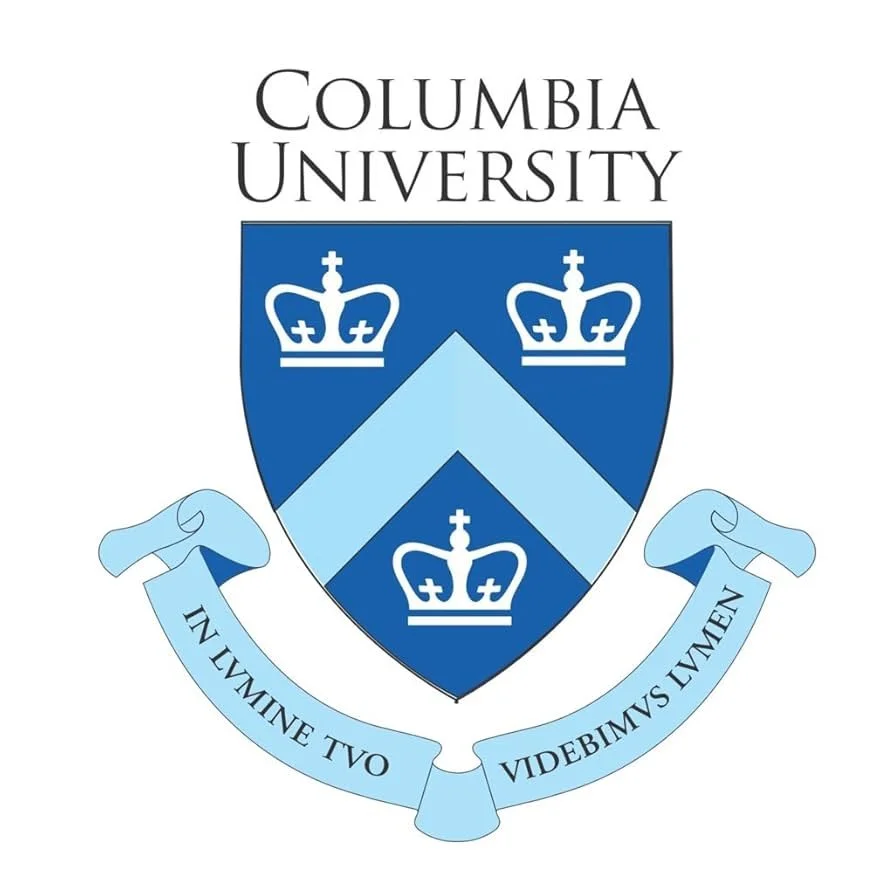 Columbia University emblem featuring a shield with blue backgrounds, crowns, and chevrons, topped with the university name and a Latin motto on a ribbon at the bottom.