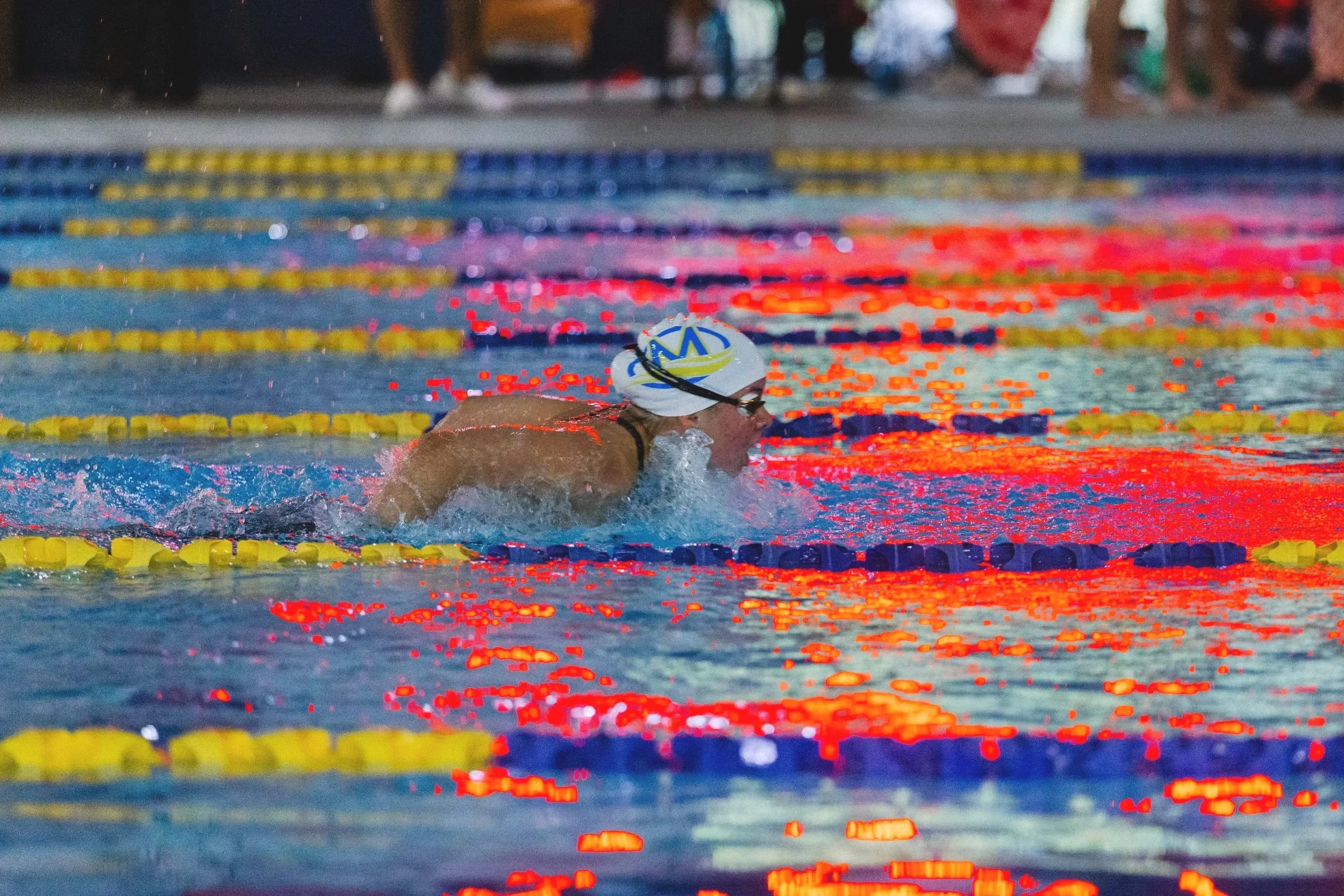 Swimmer in a pool tackling a race, wearing a swim cap and goggles.