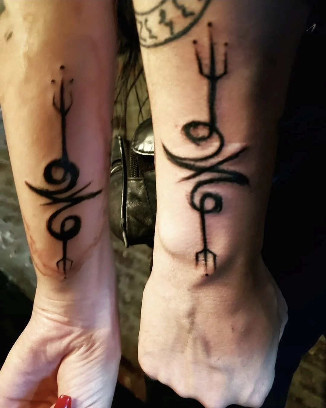 Shea Bilé and Luzia Lowe don matching black tattoo designs on their arms - The Sigil of the Crowned King. 