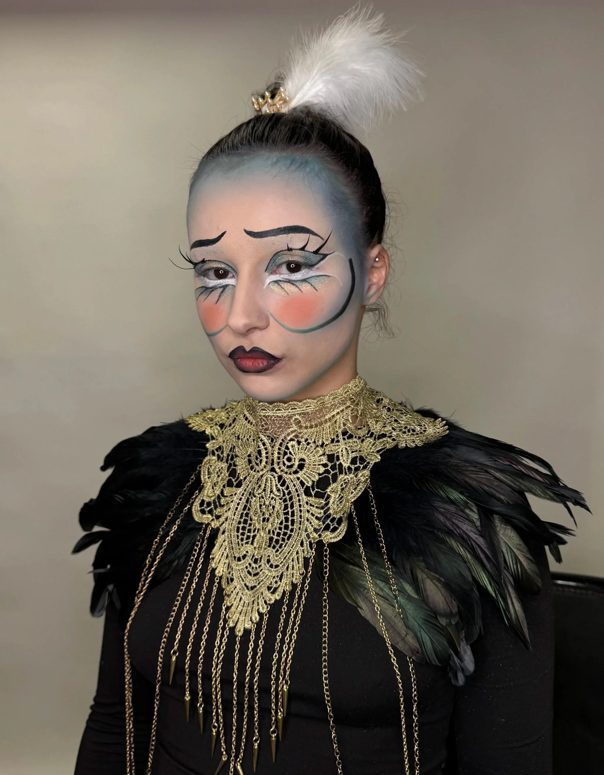 Une femme en maquillage artistique avec des traits de style caricature, portant un collier en dentelle dorée et une cape de plumes noires.