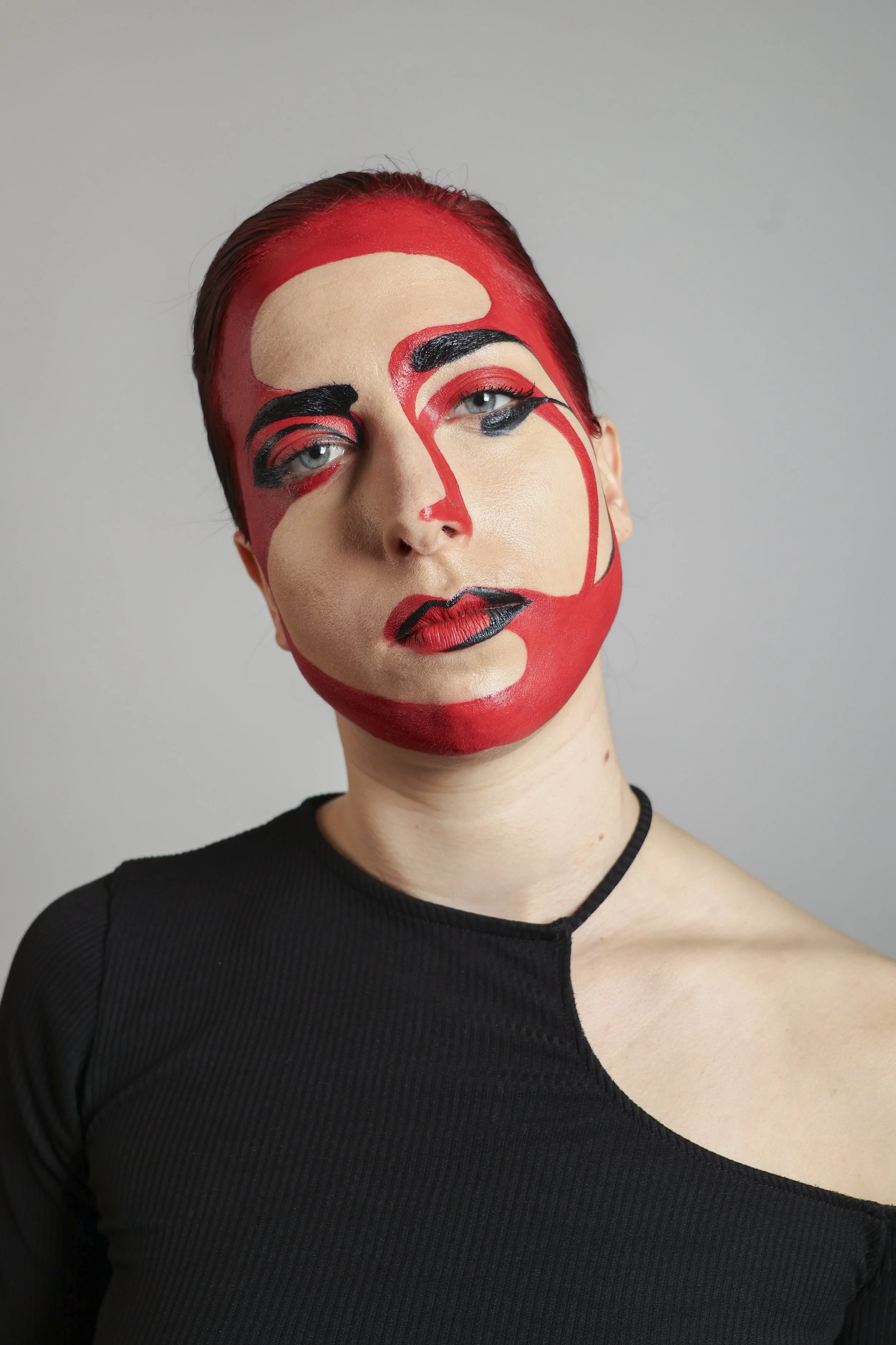Une femme avec un maquillage artistique qui ressemble à une peinture abstraite avec des couleurs rouge, beige et noir sur son visage.