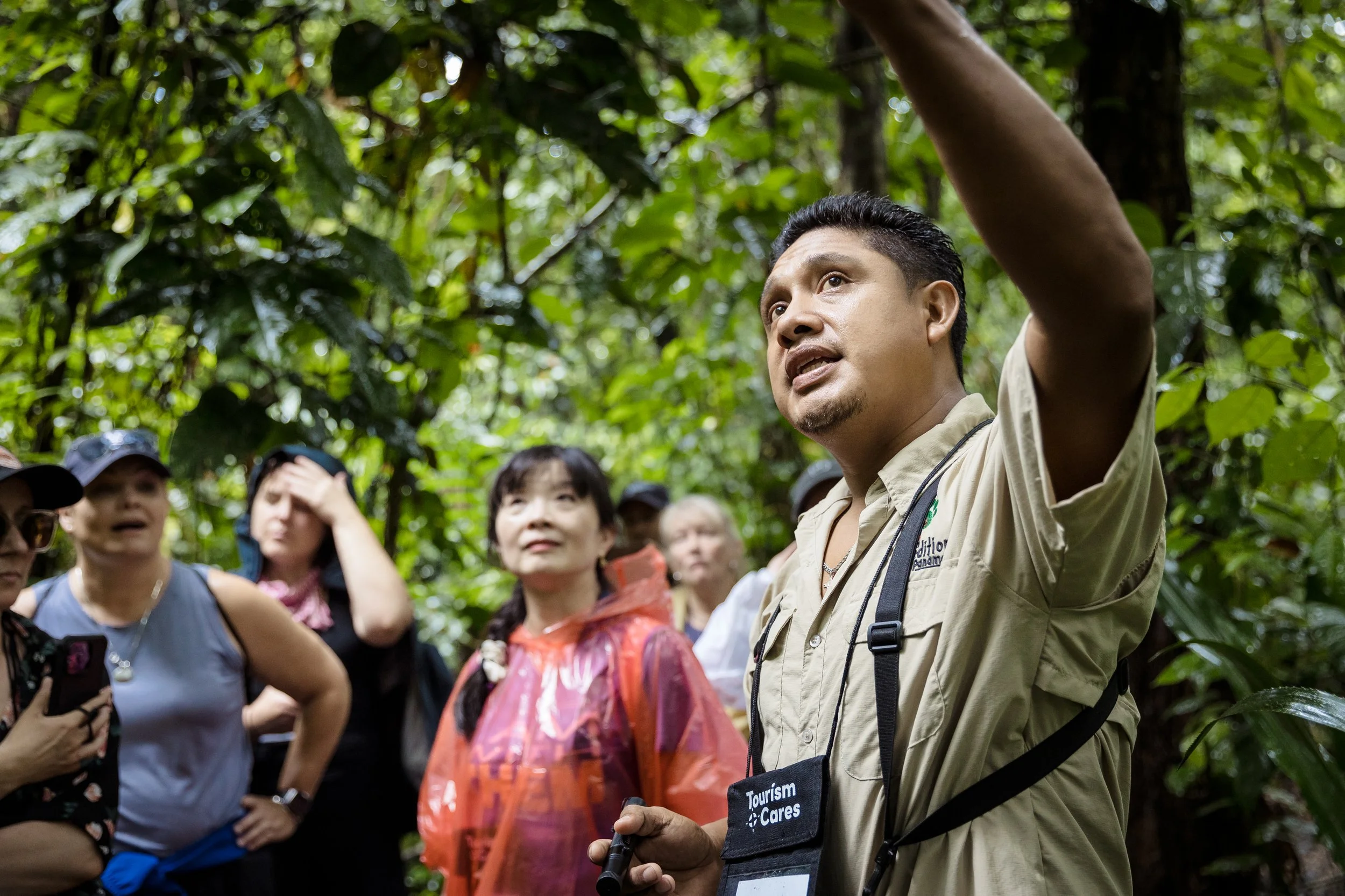 A man stands in a forest and gives a hiking tour to a group of people.