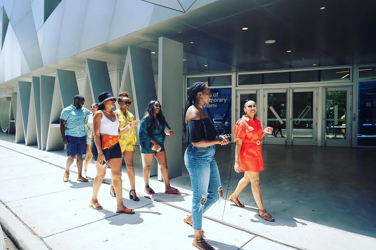 Three people posing for a photo in front of a large wooden door, with two people taking the picture.