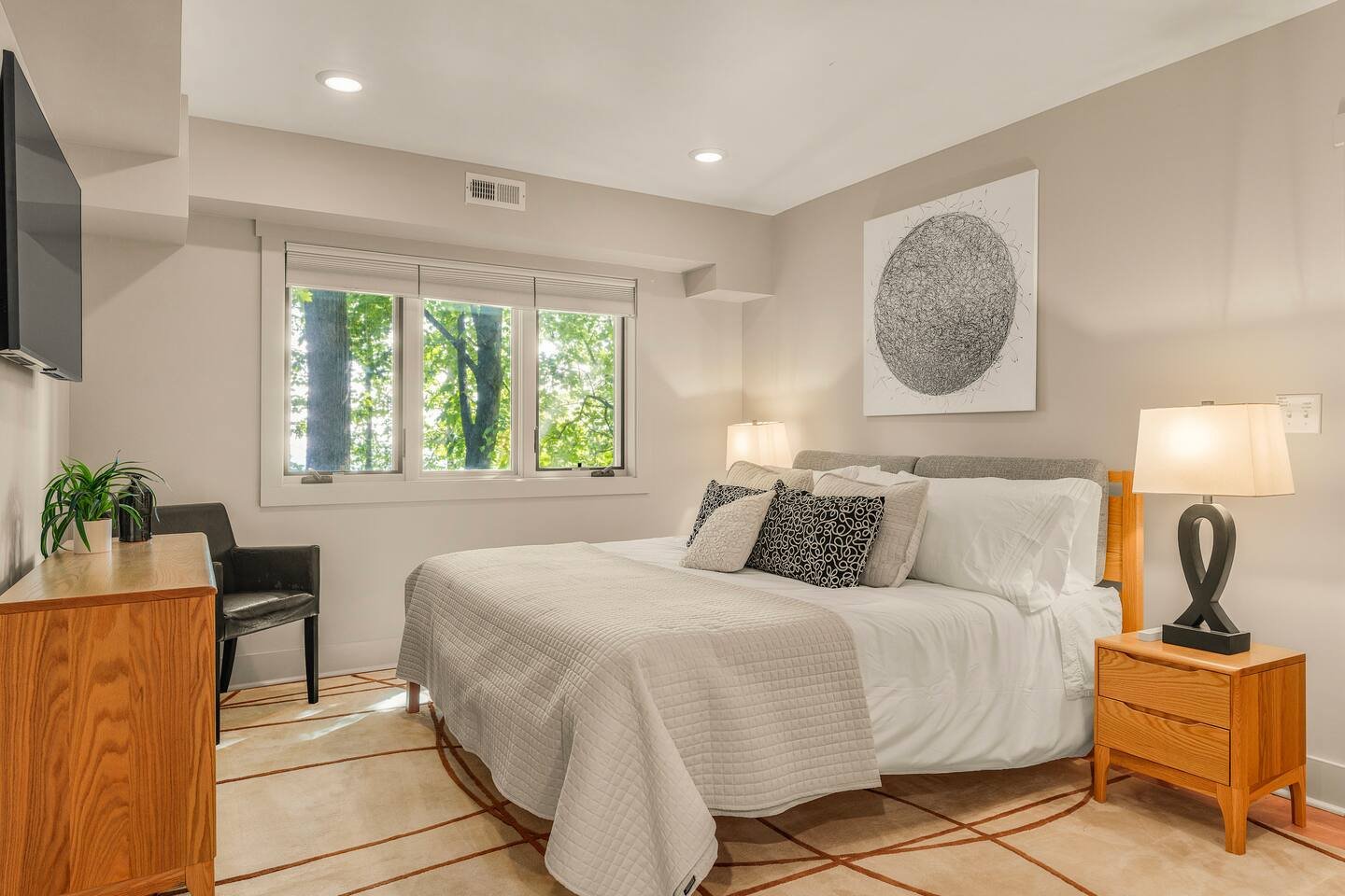 A cozy bedroom with a large bed, nightstand, and black and white artwork above the headboard