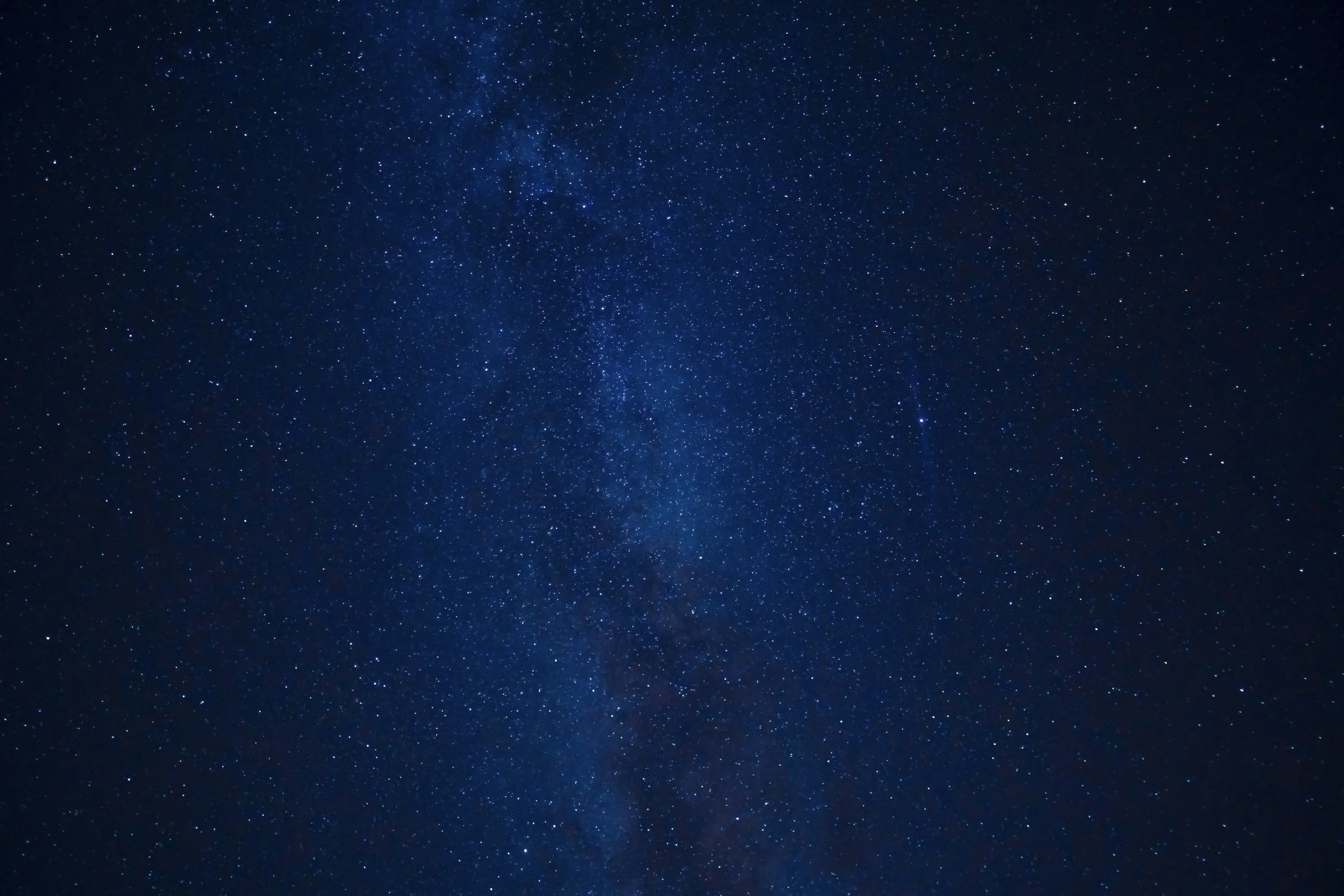 Night sky filled with countless stars and some faint Milky Way galaxy visible.