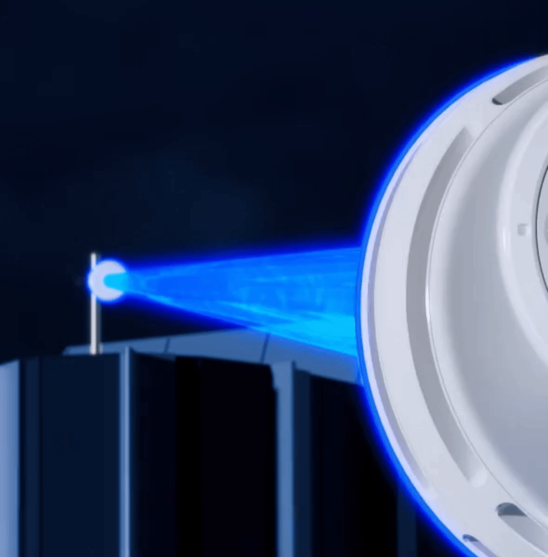 Close-up of a medical device with a blue laser or light beam projecting from it in a dark environment.