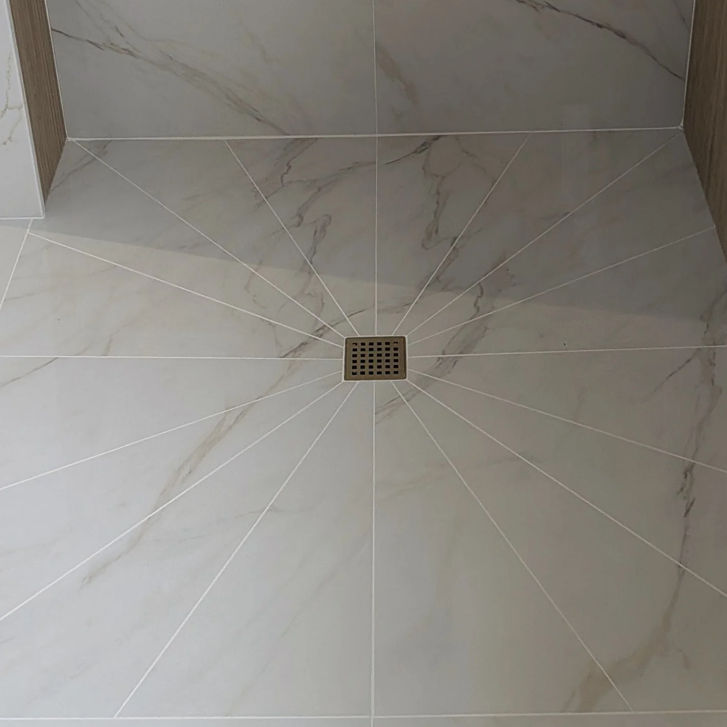 Marble tiled shower floor with a central metal drain.