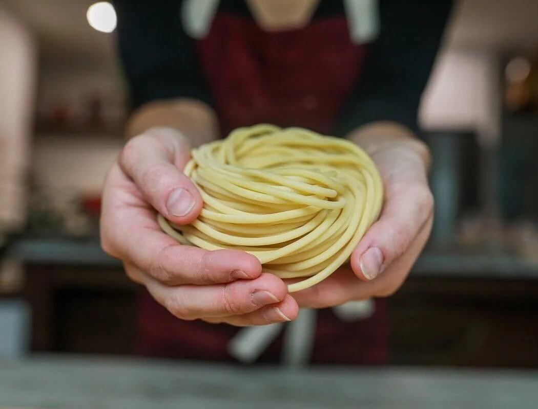 Person holding a nest of uncooked spaghetti pasta.