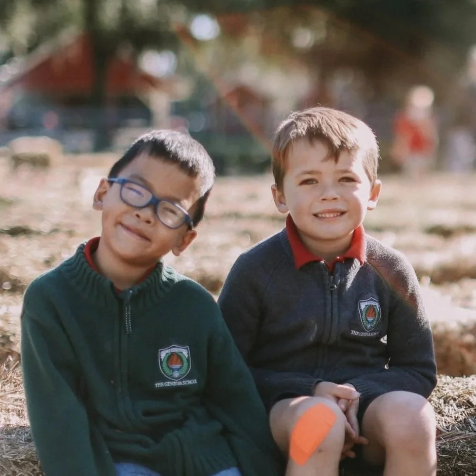 Two young boys sitting outdoors, smiling at the camera.