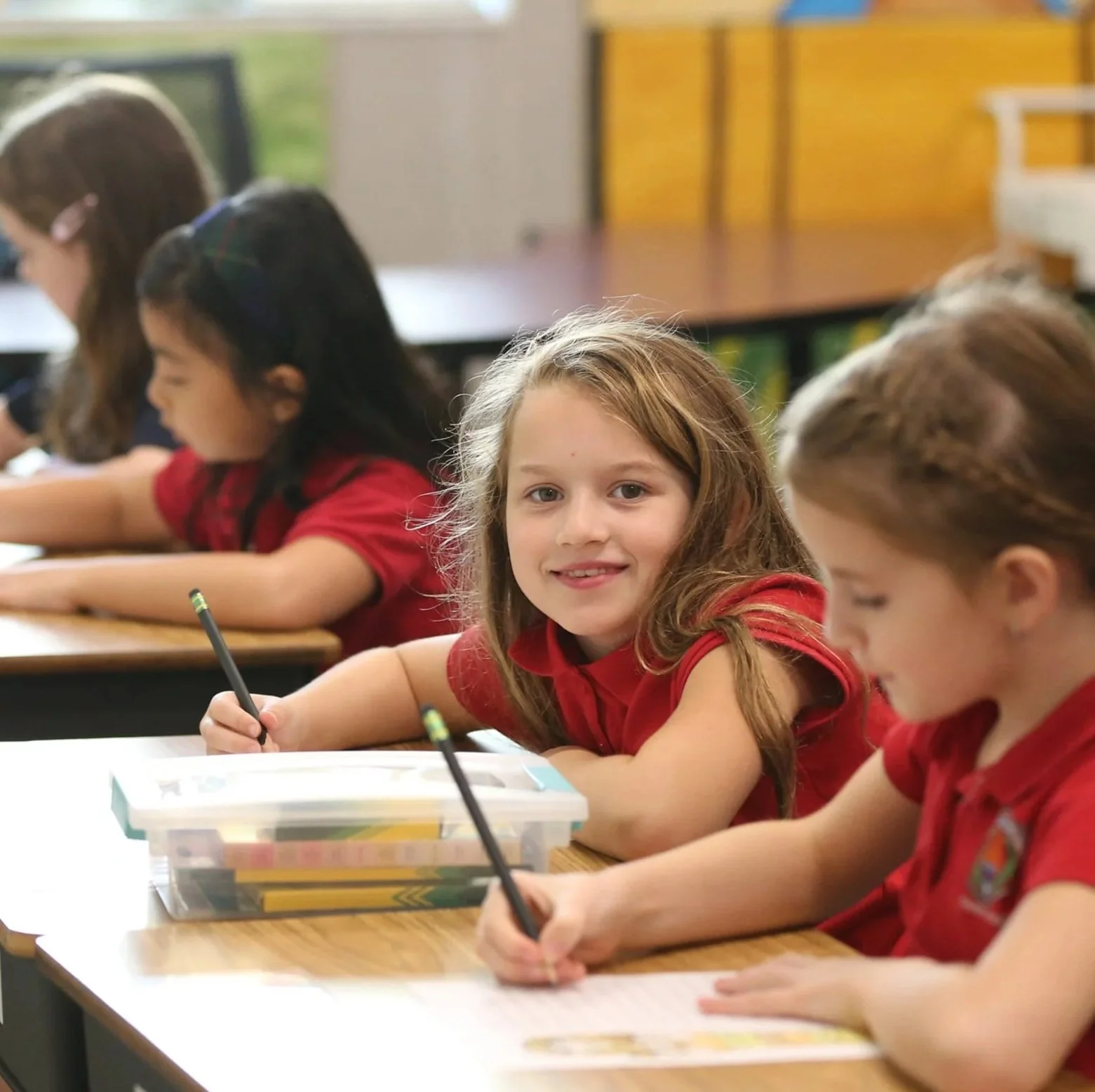 A group of young students sitting at desks in a classroom, working on assignments.