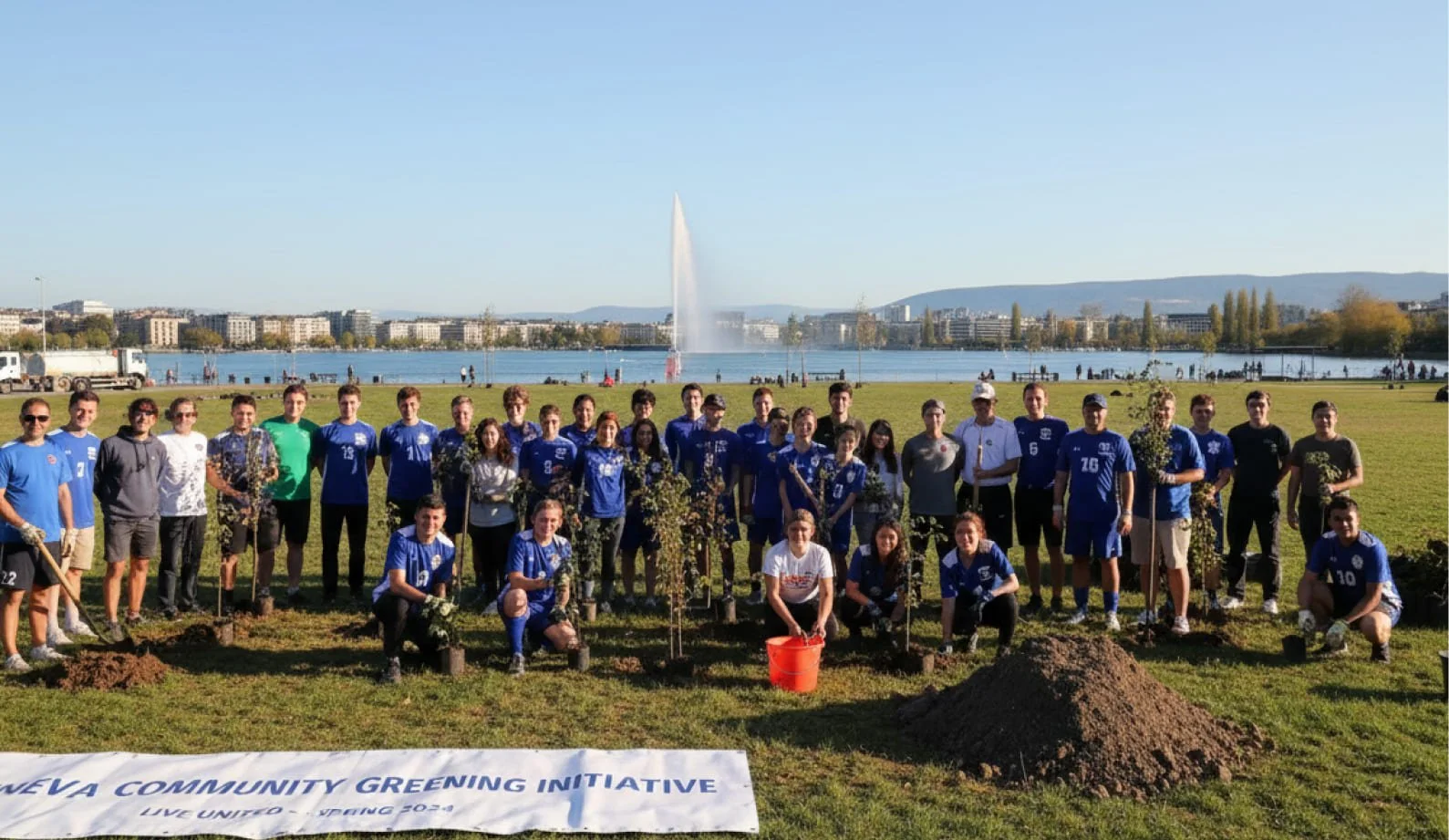 Group of people planting trees in a park by a lake with a fountain, buildings, and mountains in the background, during a community greening event.