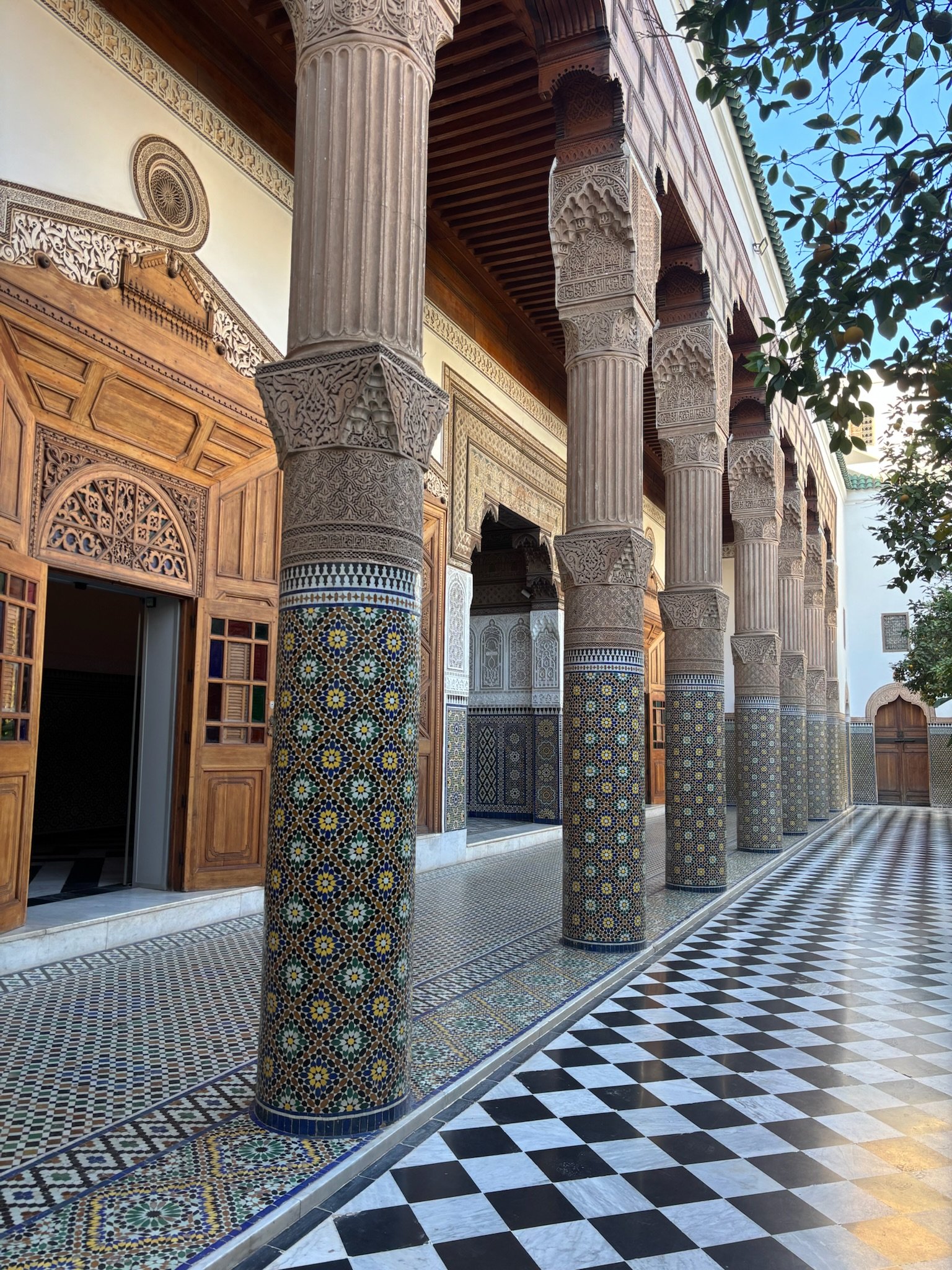 Dar El Bacha in Marrakech, featuring intricate tilework, carved architectural details, and a peaceful courtyard passage.