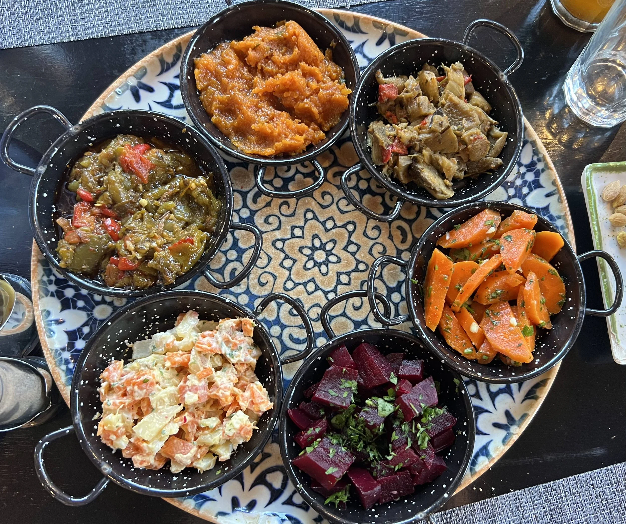 An assortment of Moroccan salads and cooked vegetable dishes served in small bowls on a decorative platter.