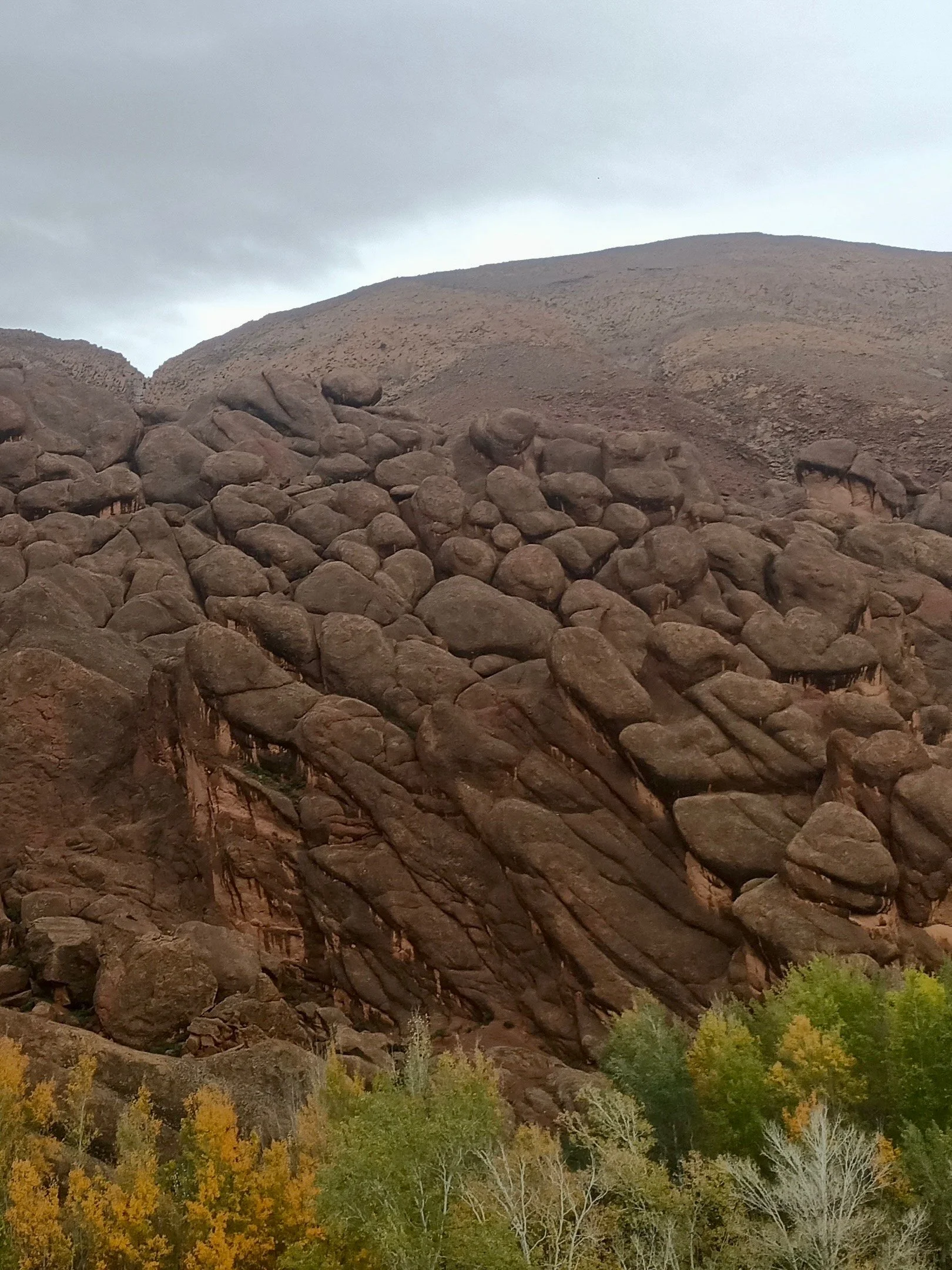 Large rocky mountain with prominent boulders, surrounded by trees with autumn foliage.