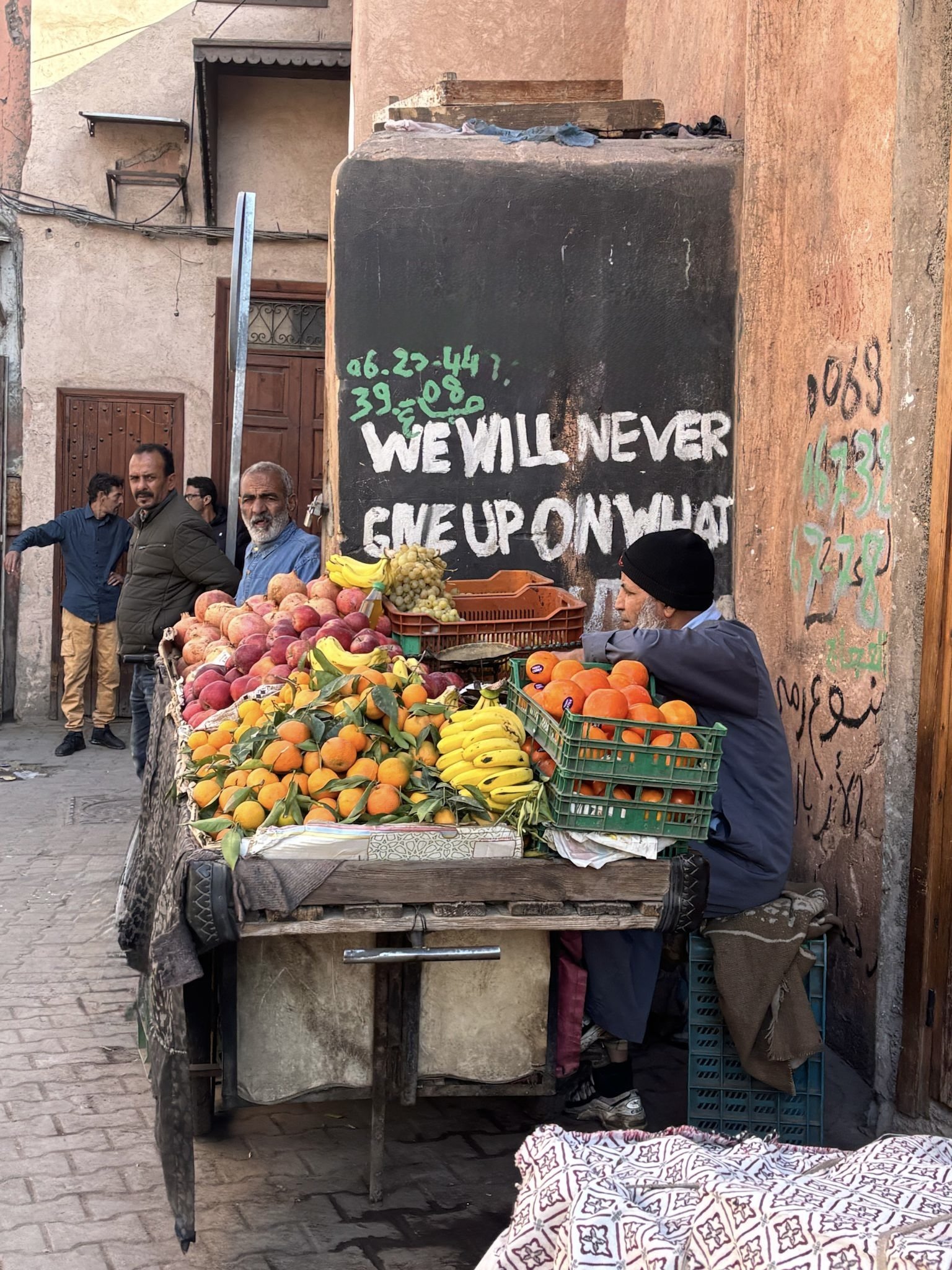Street vendor selling fresh fruit from a cart in a Moroccan market street.