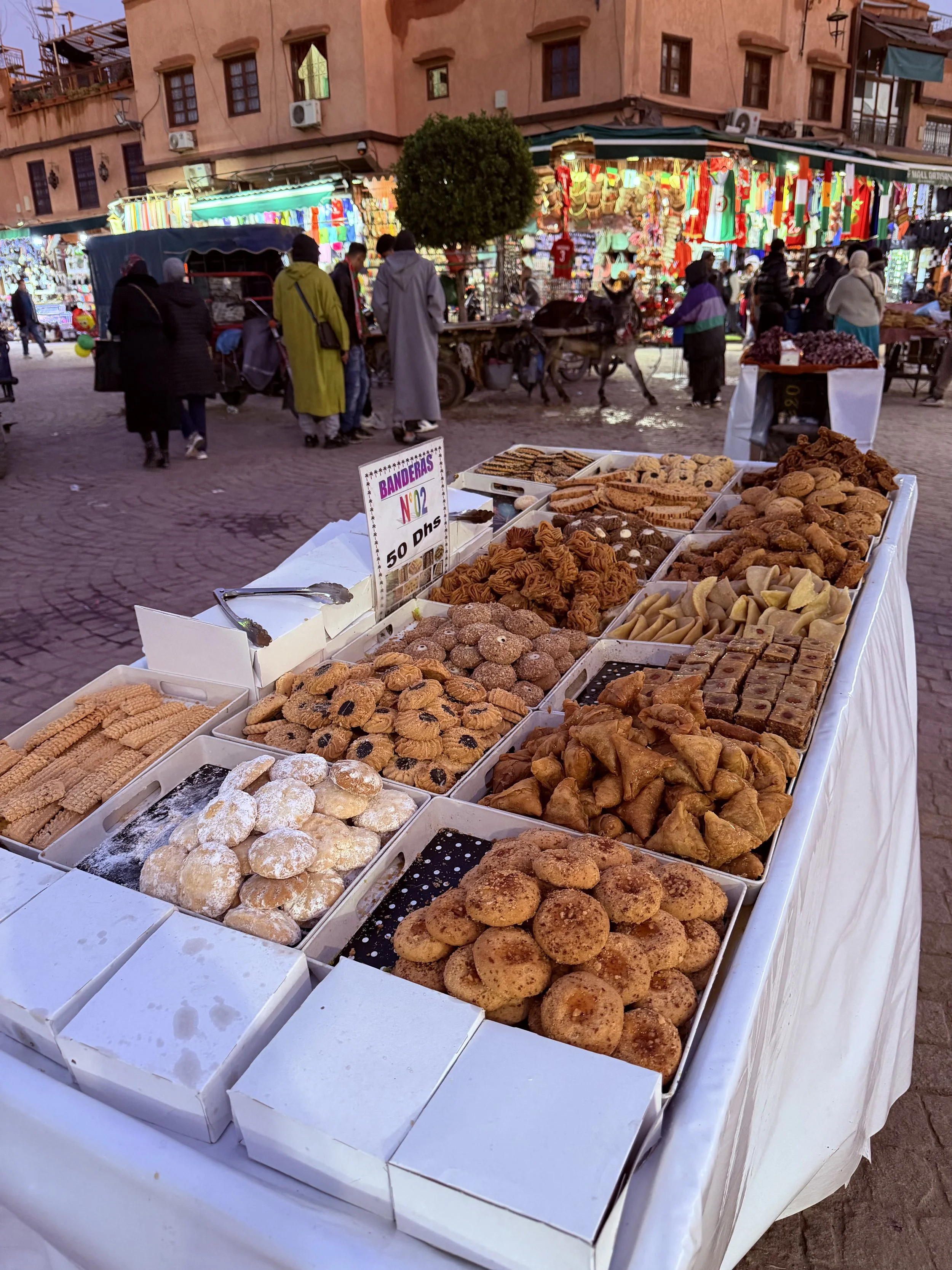 Moroccan cookies and baked goods displayed at an outdoor market stall in Marrakech.