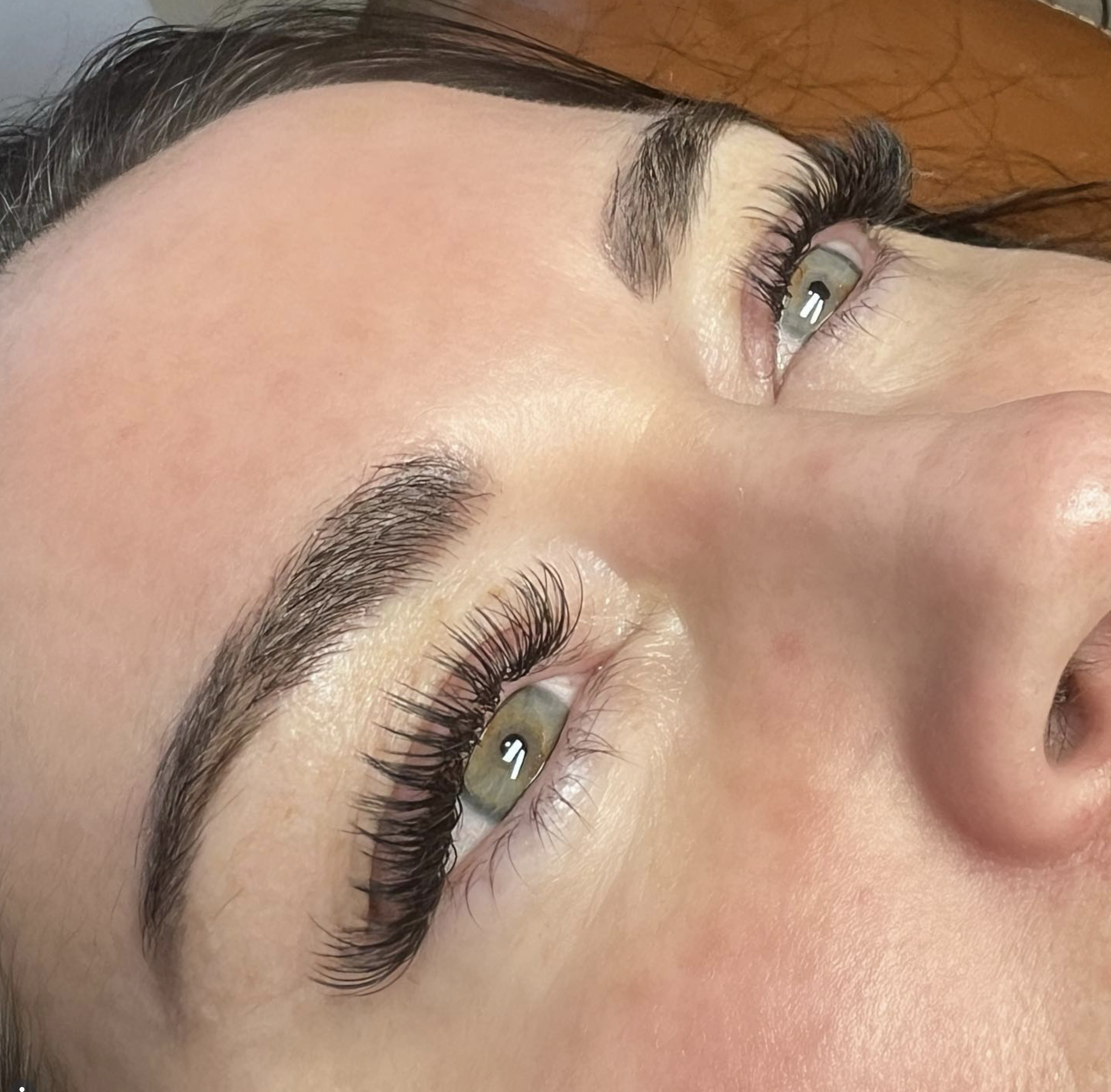 Close-up of a woman's face showing her eyes with long, curled lashes and well-groomed eyebrows.