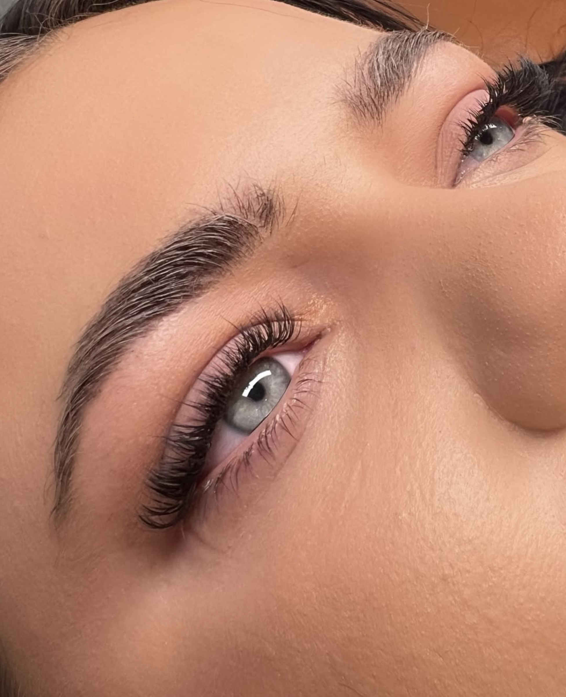 Close-up of a person's face focusing on the eyes, with makeup and styled eyebrows.
