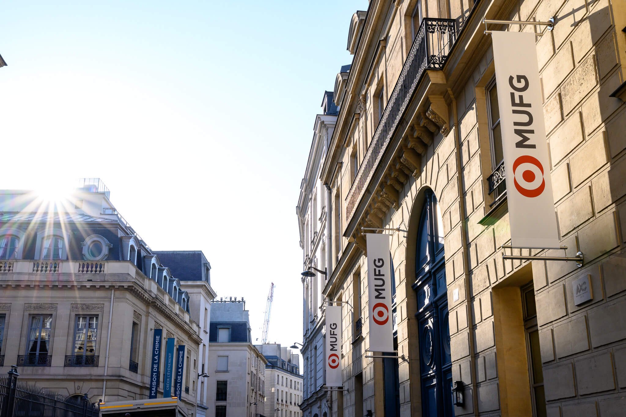 Parisian city street with historic buildings, banners with MUFG  logos