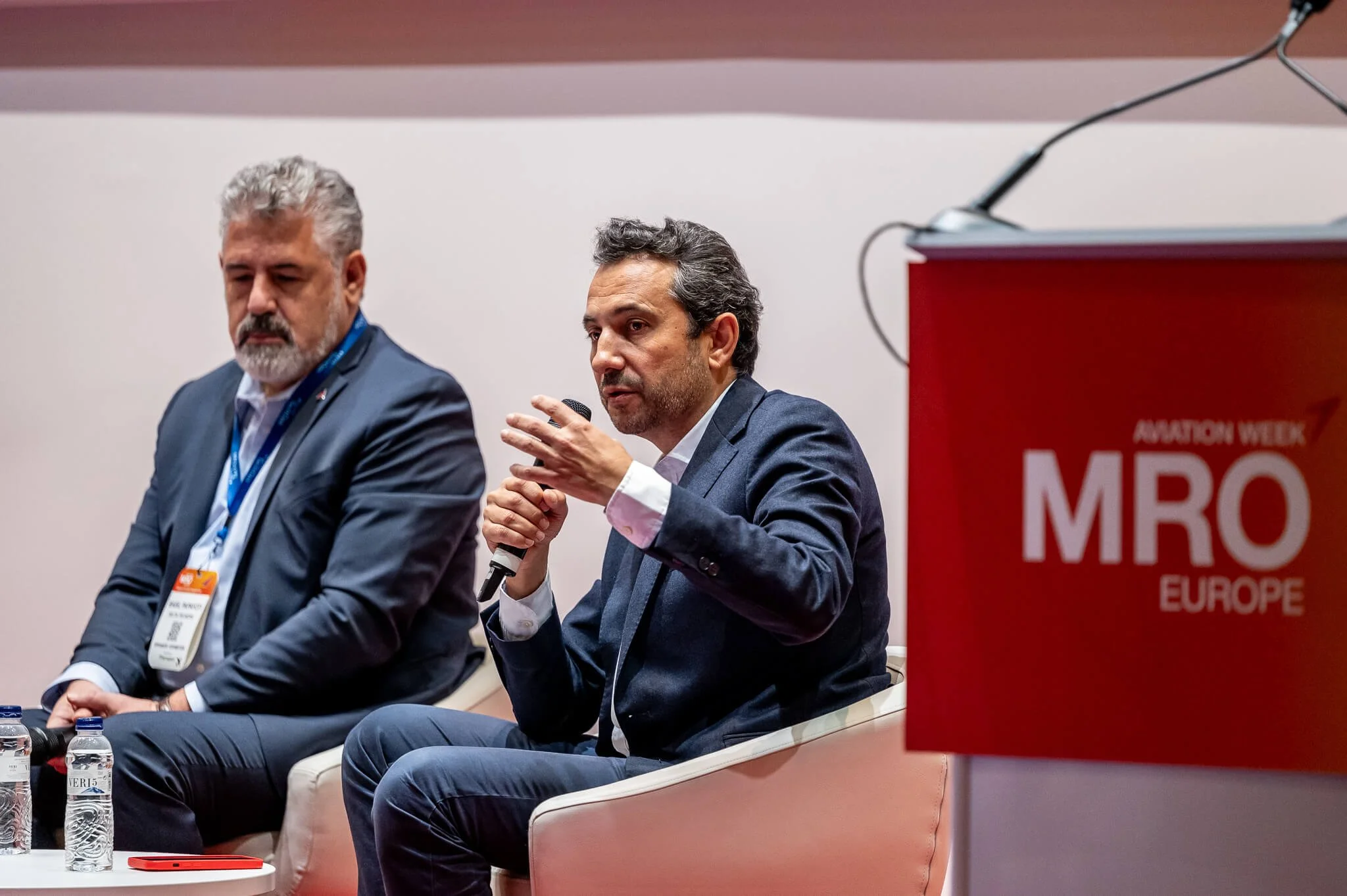 Two men participating in a panel discussion at an event 
