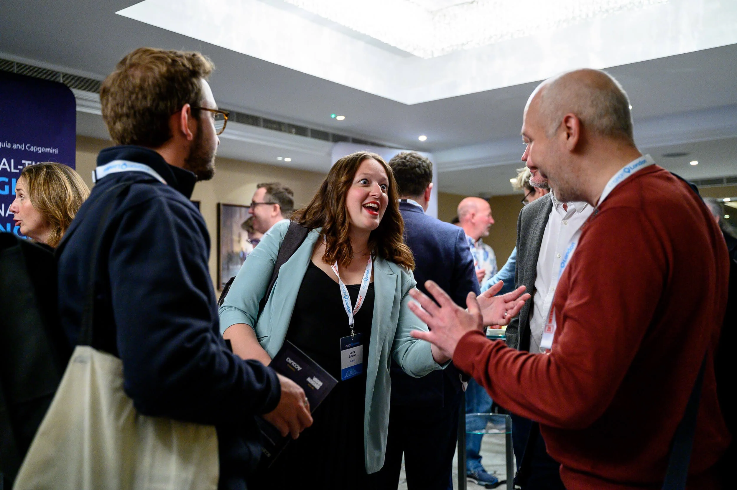 Group of people at a professional conference, engaging in conversation and networking indoors.