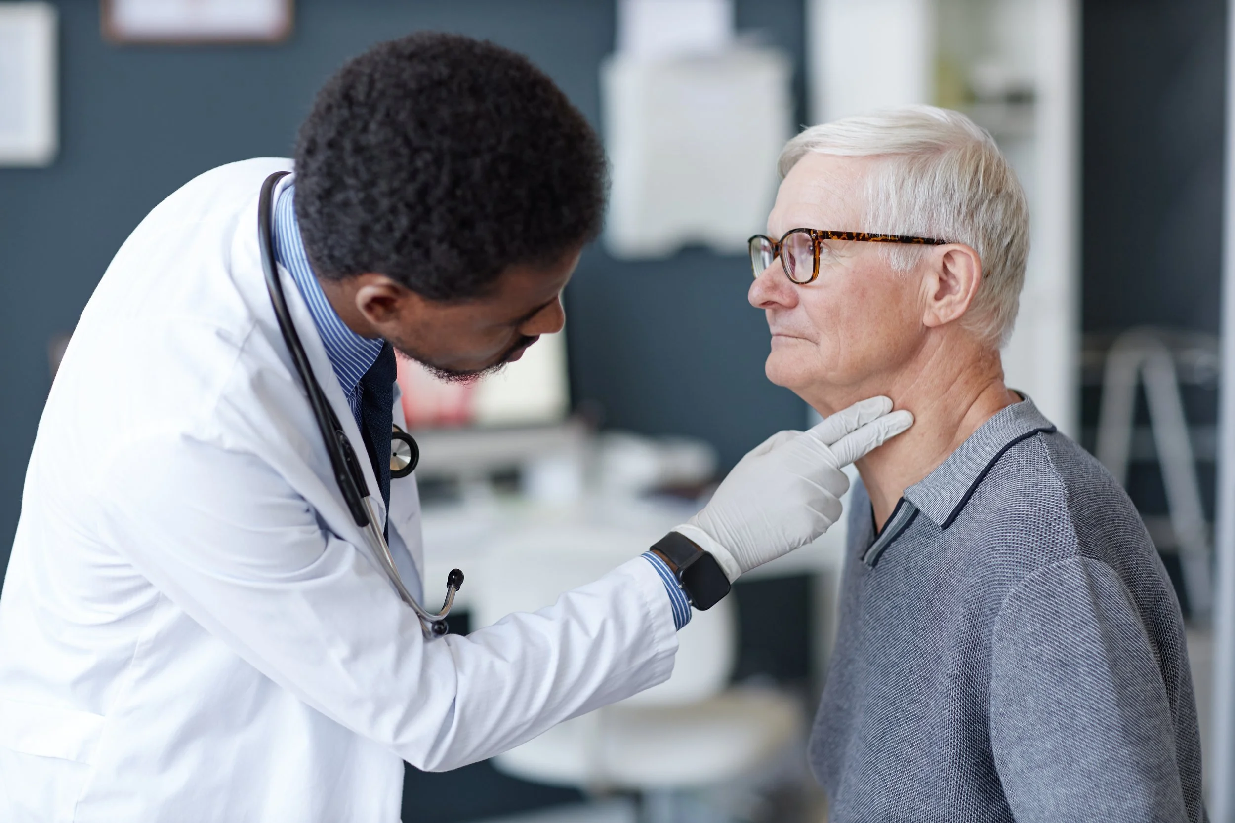 Doctor examining an elderly man in a medical office.