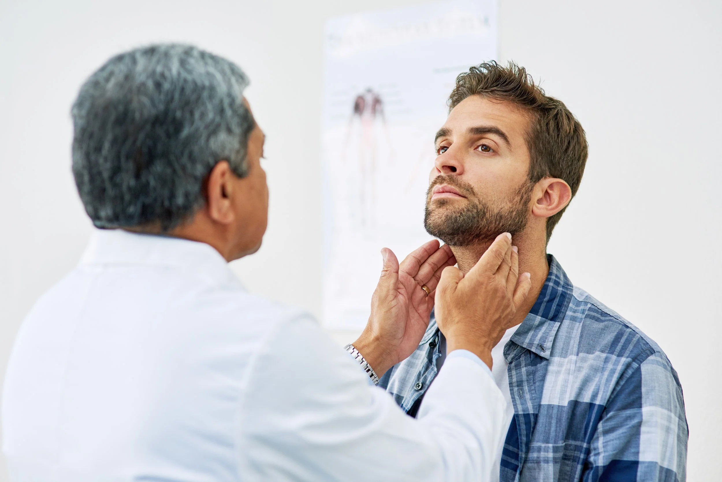 Doctor examining a man's throat in a medical office.