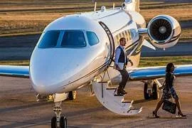 Person boarding a private jet on an airport tarmac.