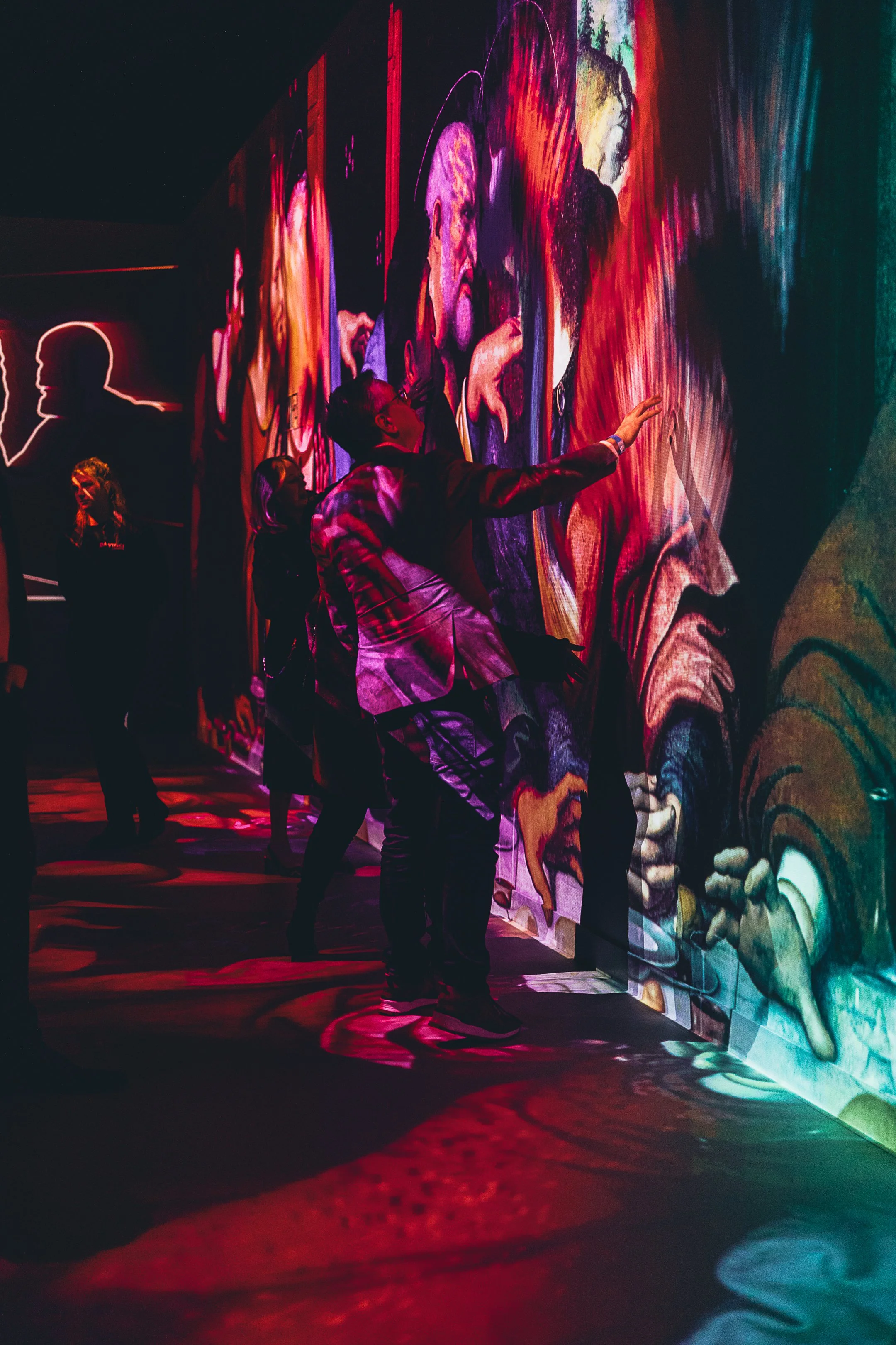 People viewing a colorful, abstract digital art installation with vivid, swirling colors and shapes.