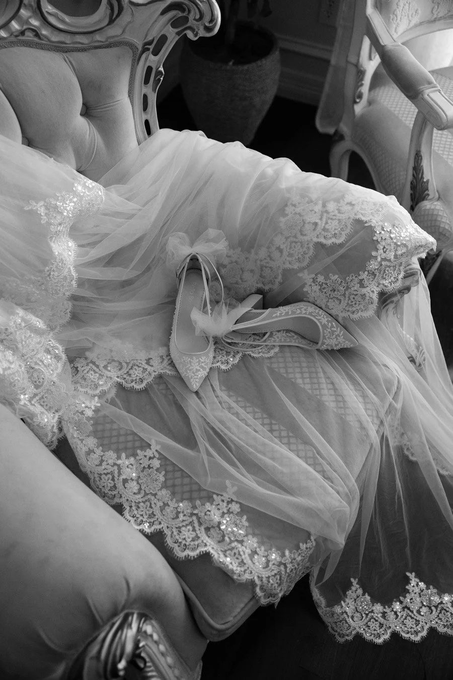 A wedding dress and high heels on an ornate vintage couch.
