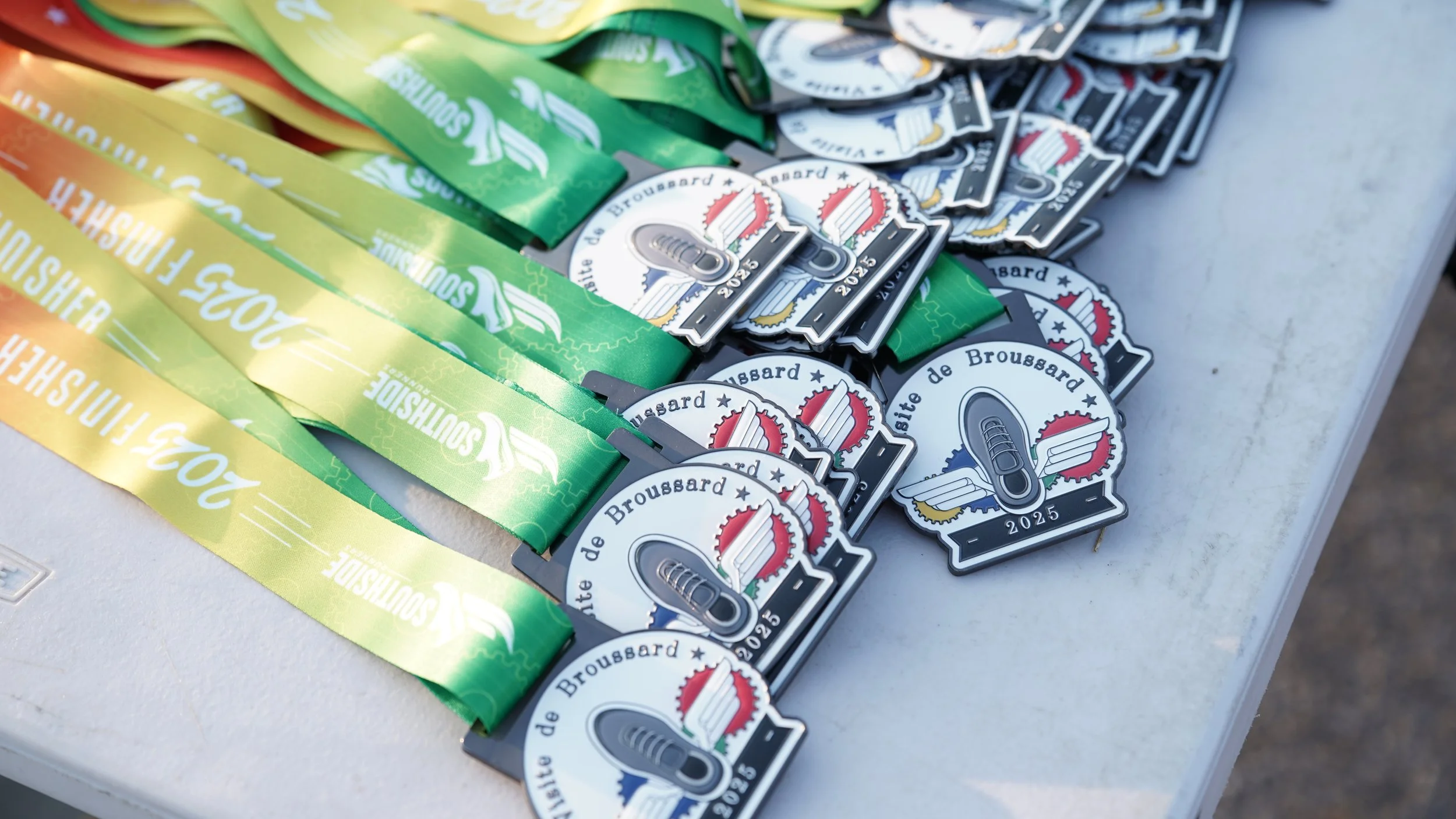Medals and ribbons for the 2023 Bourse de Brousard event displayed on a table.