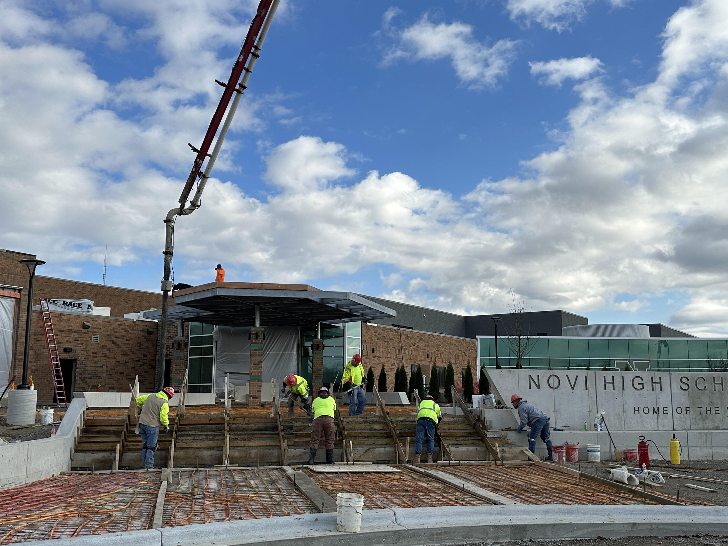 Construction workers pouring concrete stairs at the new Novi High School fitness center expansion project.