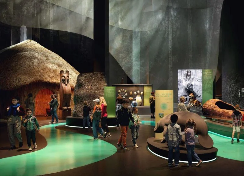 People, including children, exploring a space-themed museum exhibit with model rockets, space-related displays, and a galactic ceiling.