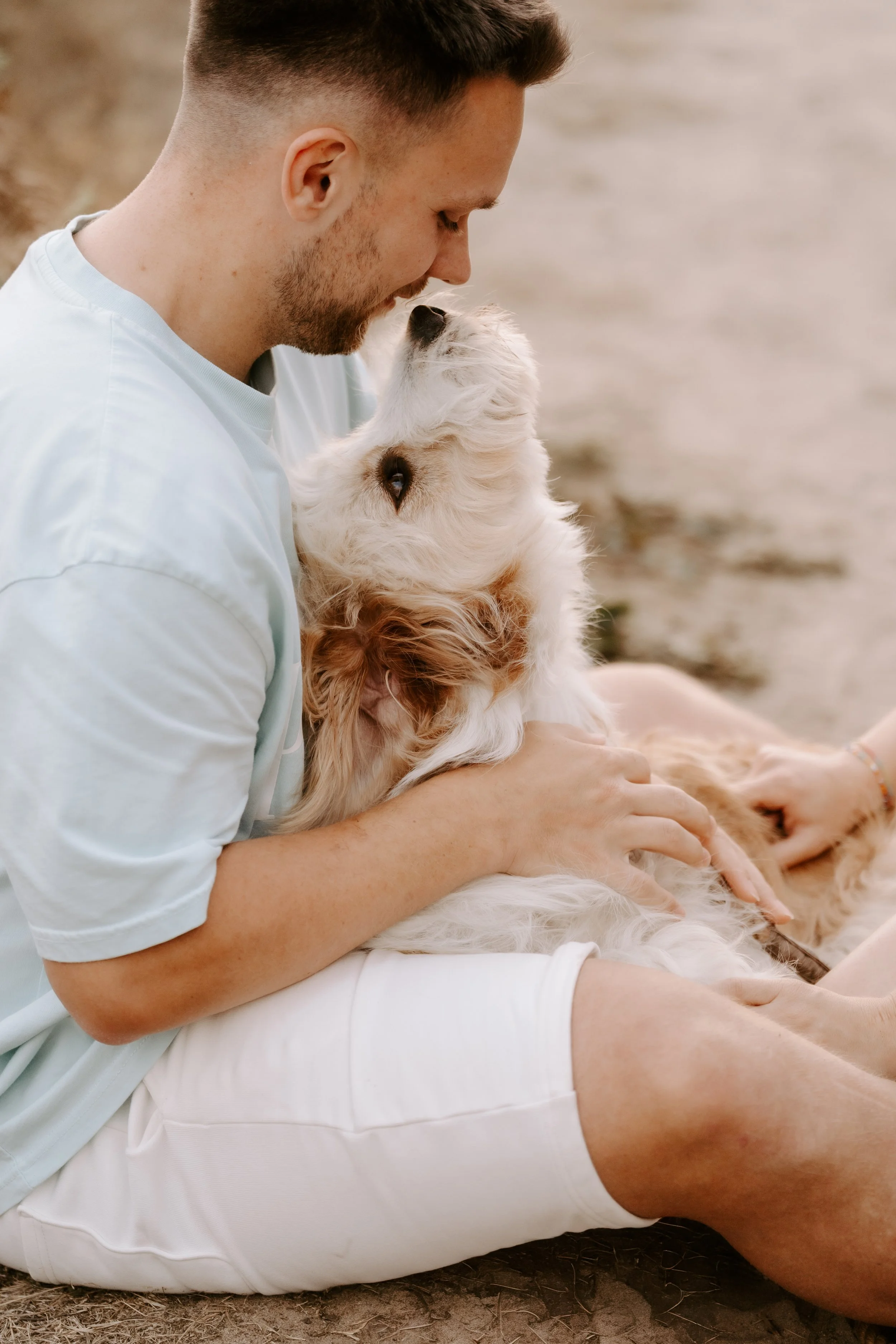 Ein Mann kuschelt mit seinem Hund in der Natur