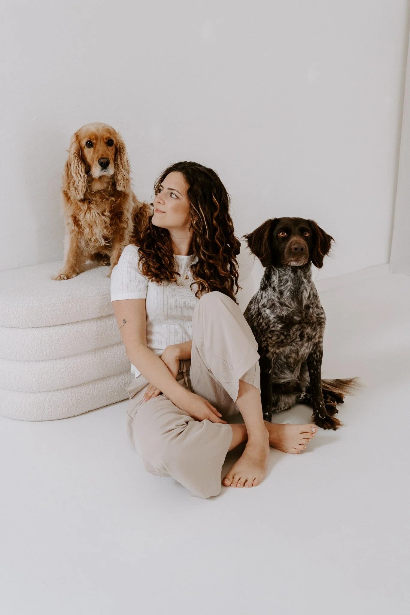 Eine Frau sitzt mit ihren zwei Hunden in einem Tageslichtstudio