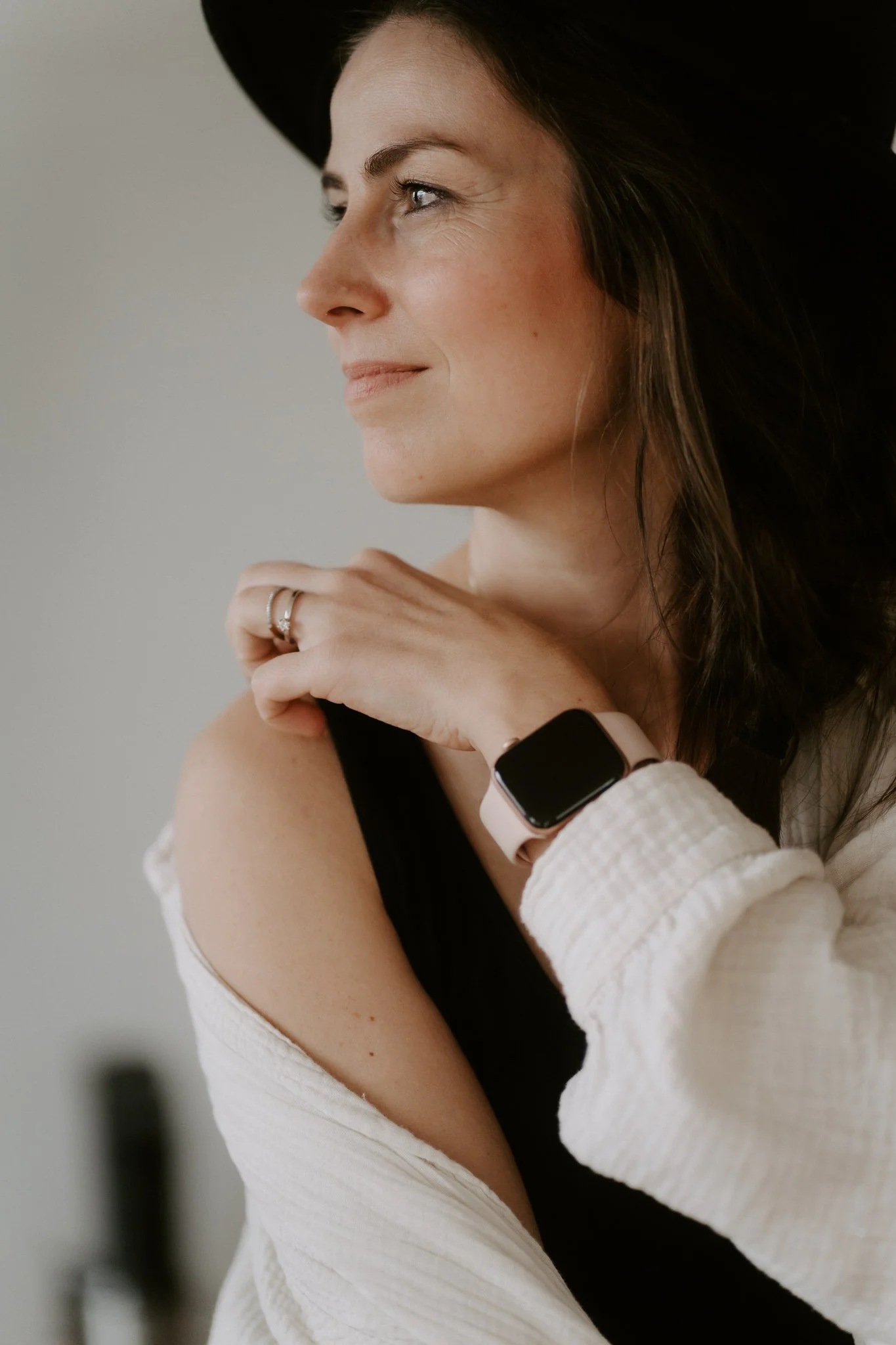 Nahaufnahme einer lächelnden Frau mit Hut, die eine Smartwatch trägt.