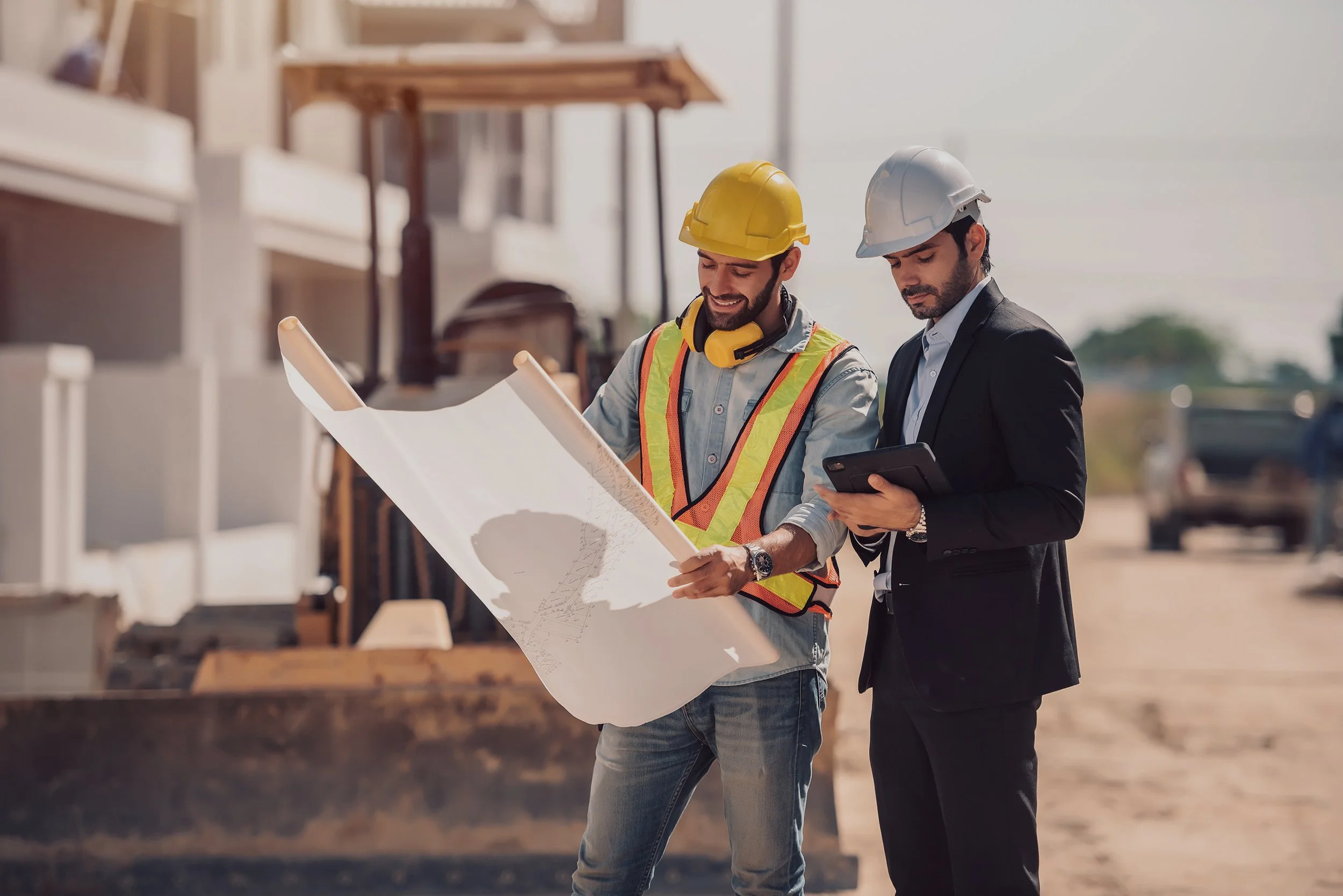 Two construction workers, one wearing a yellow safety helmet
