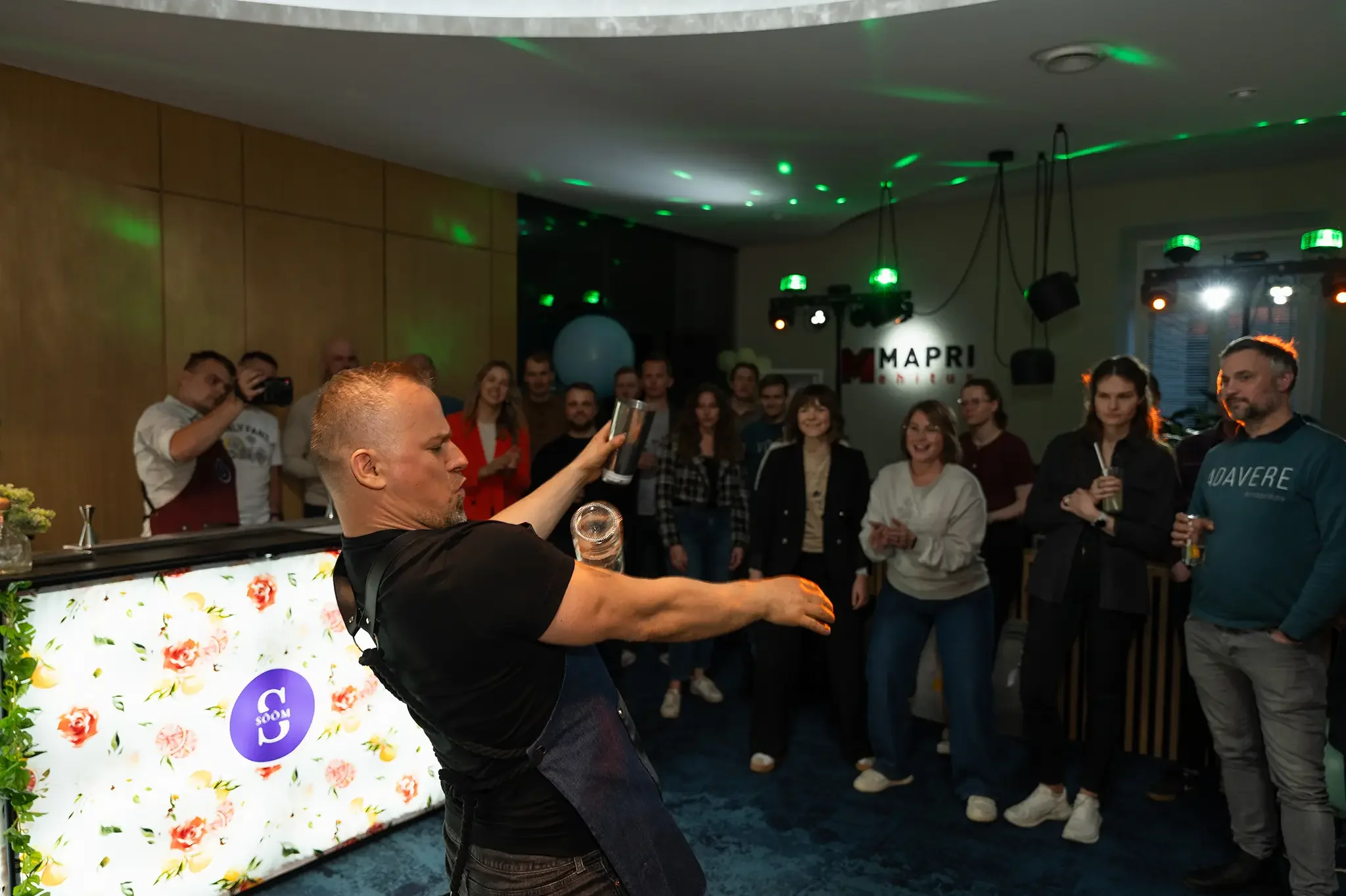 sündmuse foto baarmanist kes esineb kokteilisegamise etteastega ettevõtte üritusel siseruumis publiku ees