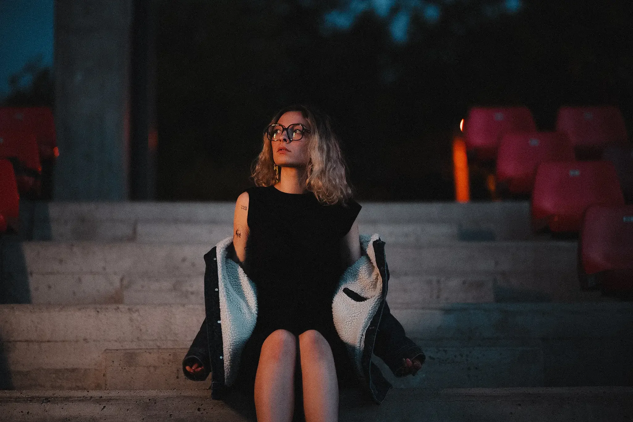 linnaportree Tartu Tammelinnas istuvast naisest Tamme staadionil hämaras valguses ja filmiliku meeleoluga