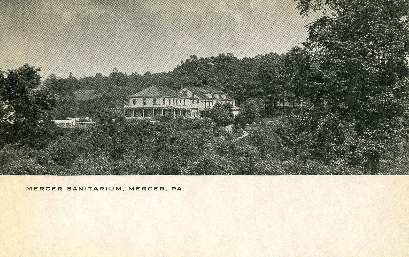 A black and white photo of a large building on a hillside surrounded by trees, labeled as Mercer Sanitarium in Mercer, PA.