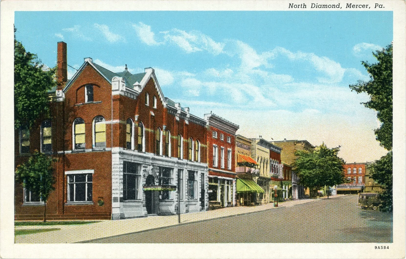 Colorized vintage photograph of Main Street in North Diamond, Mercer, Pennsylvania, with historic brick storefronts, trees lining the street, and a blue sky with some clouds.