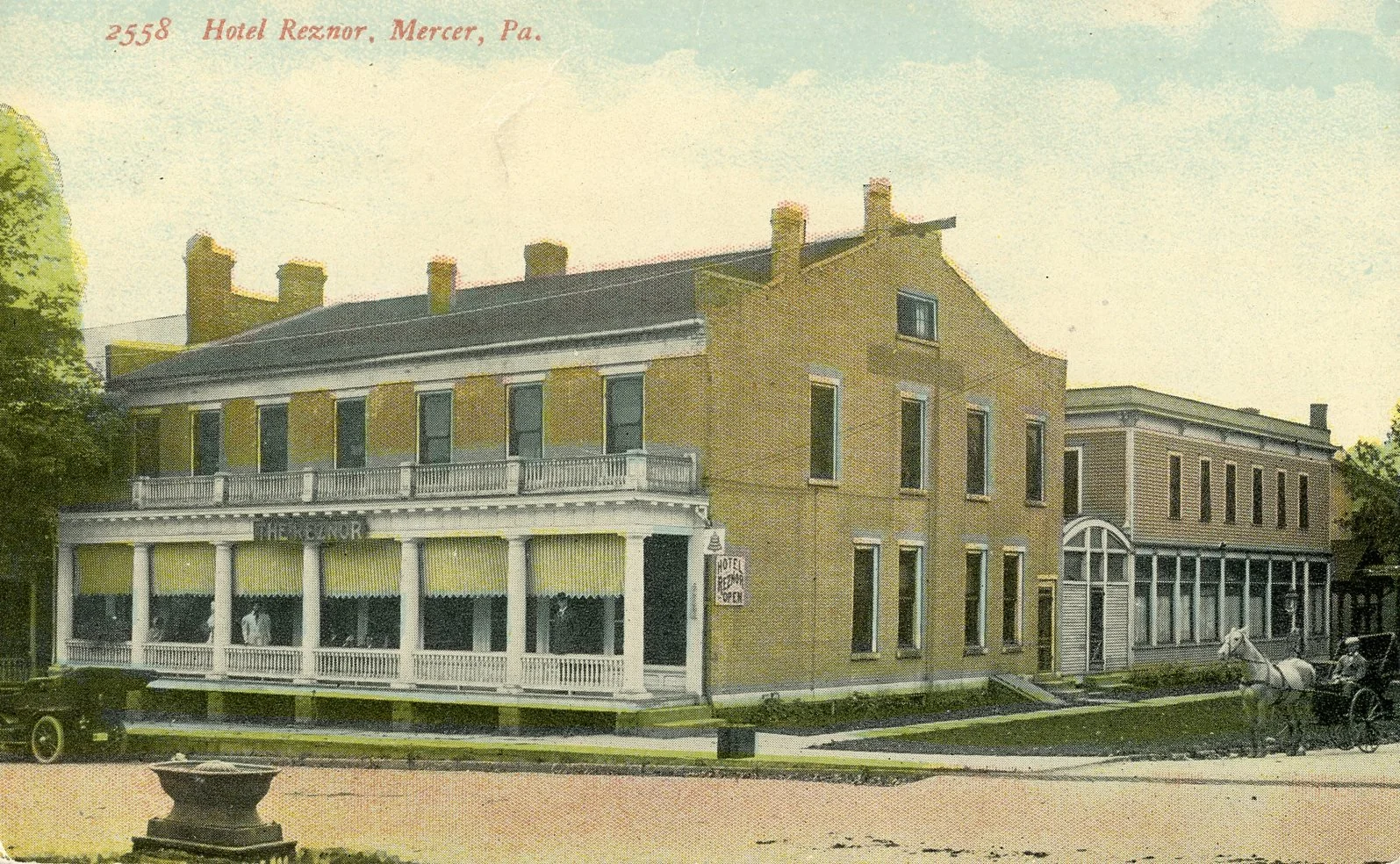 Historical photograph of the Hotel Reznor in Mercer, Pennsylvania, featuring a three-story building with a wraparound porch on the second floor, a sign for the hotel, and a horse-drawn carriage in front.
