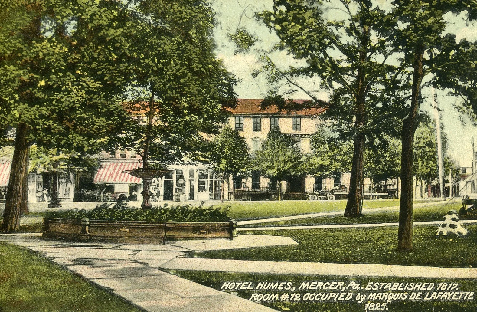 A historic street scene featuring Hotel Humes in Mercer, Pennsylvania, established in 1817, with a two-story building and several storefronts. There is a park with large trees, a fountain, park benches, and old-fashioned automobiles. The caption indi