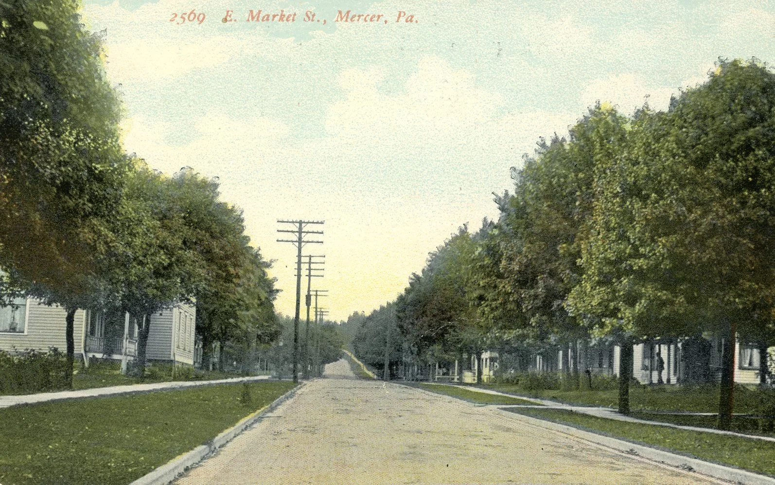 A vintage colorized photograph of East Market Street in Mercer, Pennsylvania, featuring a quiet residential street lined with trees and houses, with power lines running along the street.