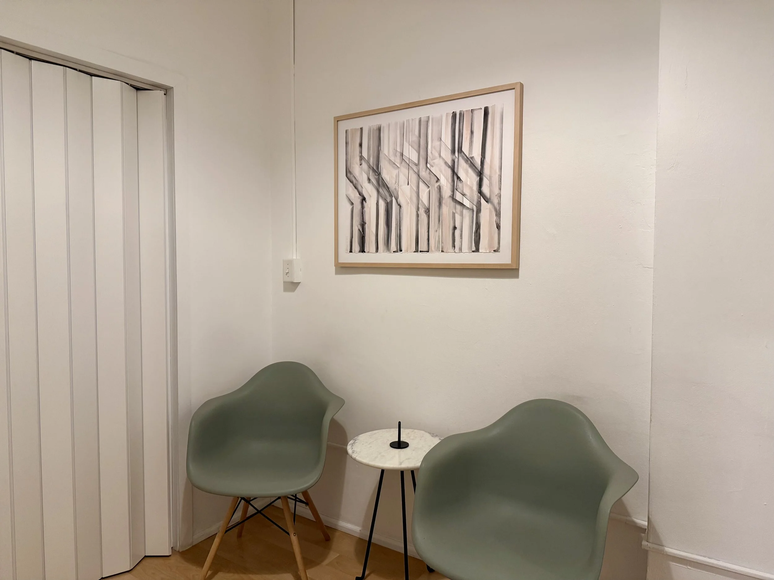 Shruthi a South Asian anxiety therapist's waiting room area which includes two chairs and picture hanging in the background
